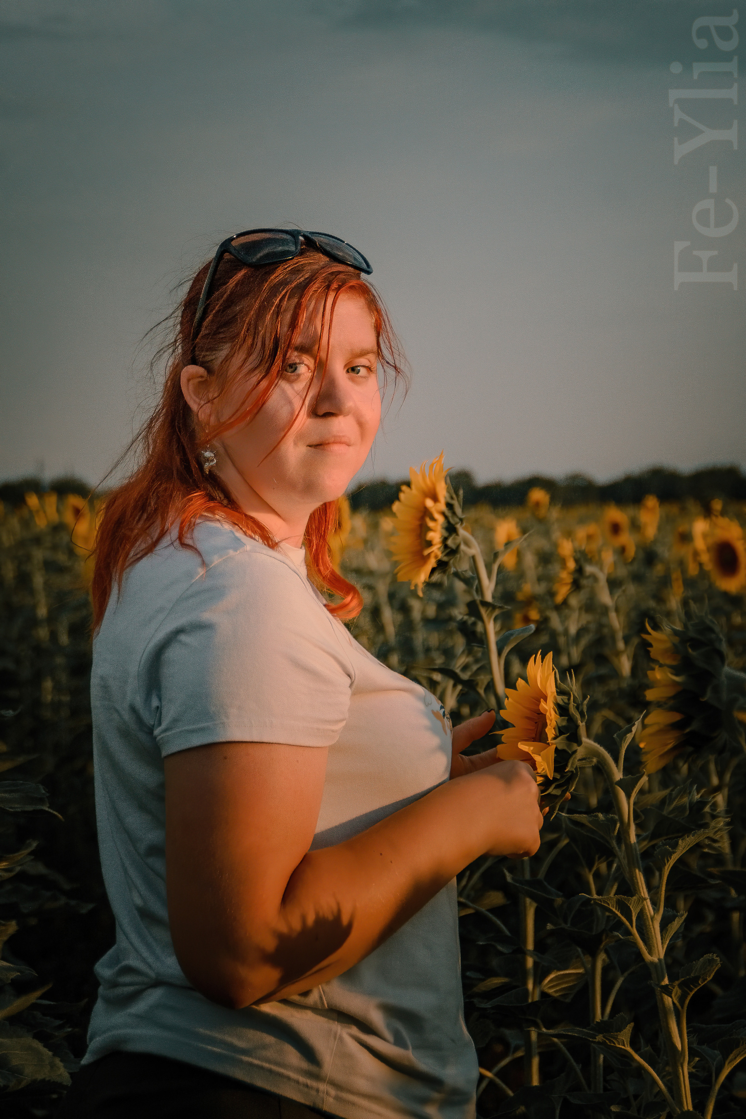 девушка стоит в поле подсолнуха и смотрит в объектив