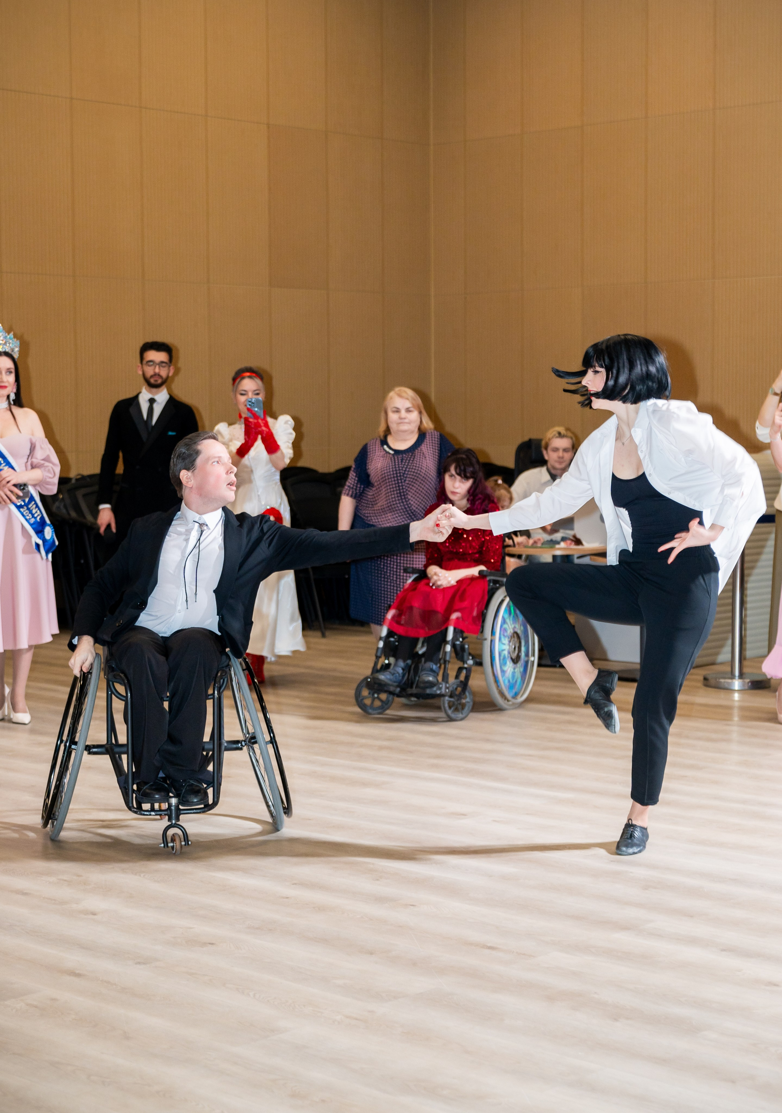 Эмоциональный танец: девушка в белой рубашке исполняет поддержку с мужчиной в инвалидной коляске на инклюзивном балу «Мы все равны». Фотограф Мальцев Евгений.