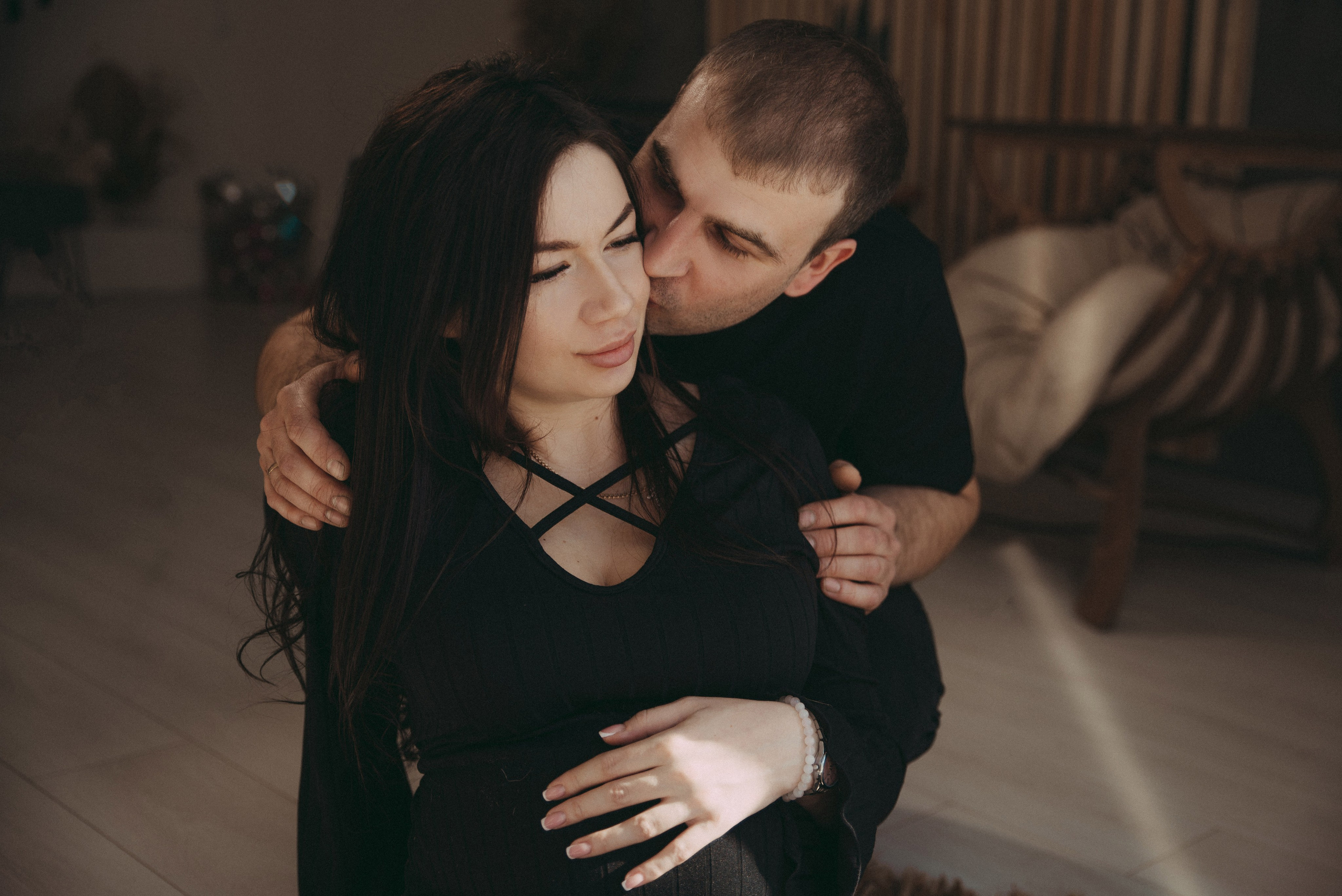 семейная пара в черном у окна целуется