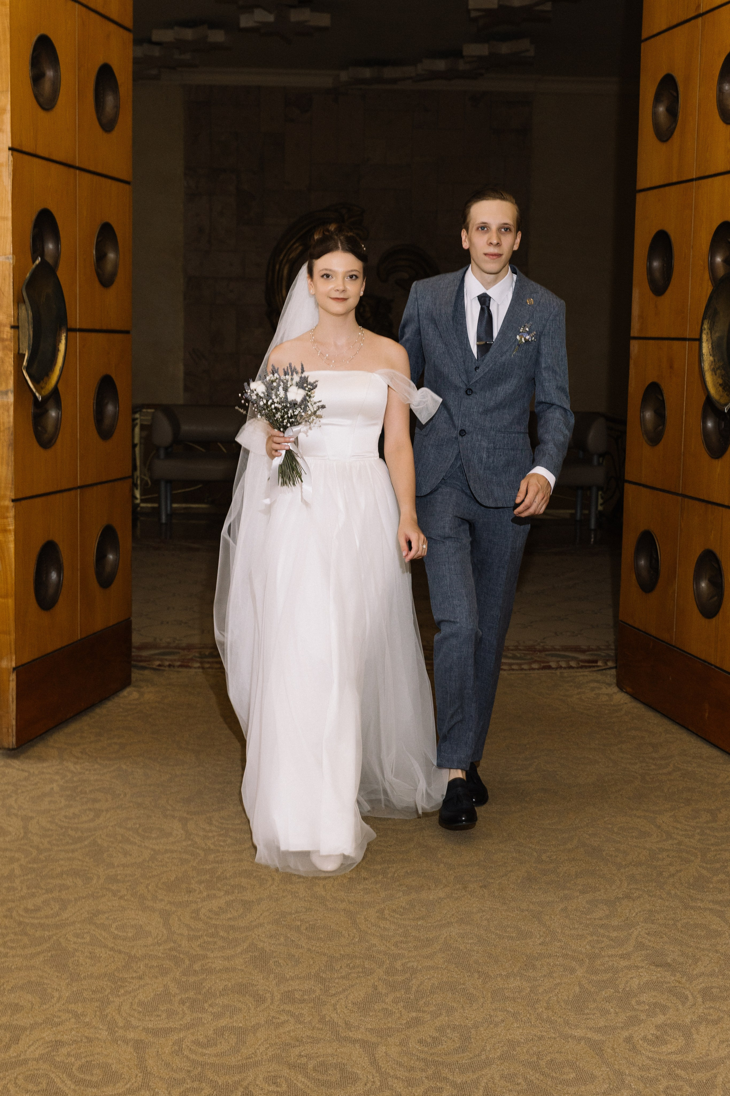 Новобрачные проходят по дорожке, рассеянный свет свечей и лепестков роз.