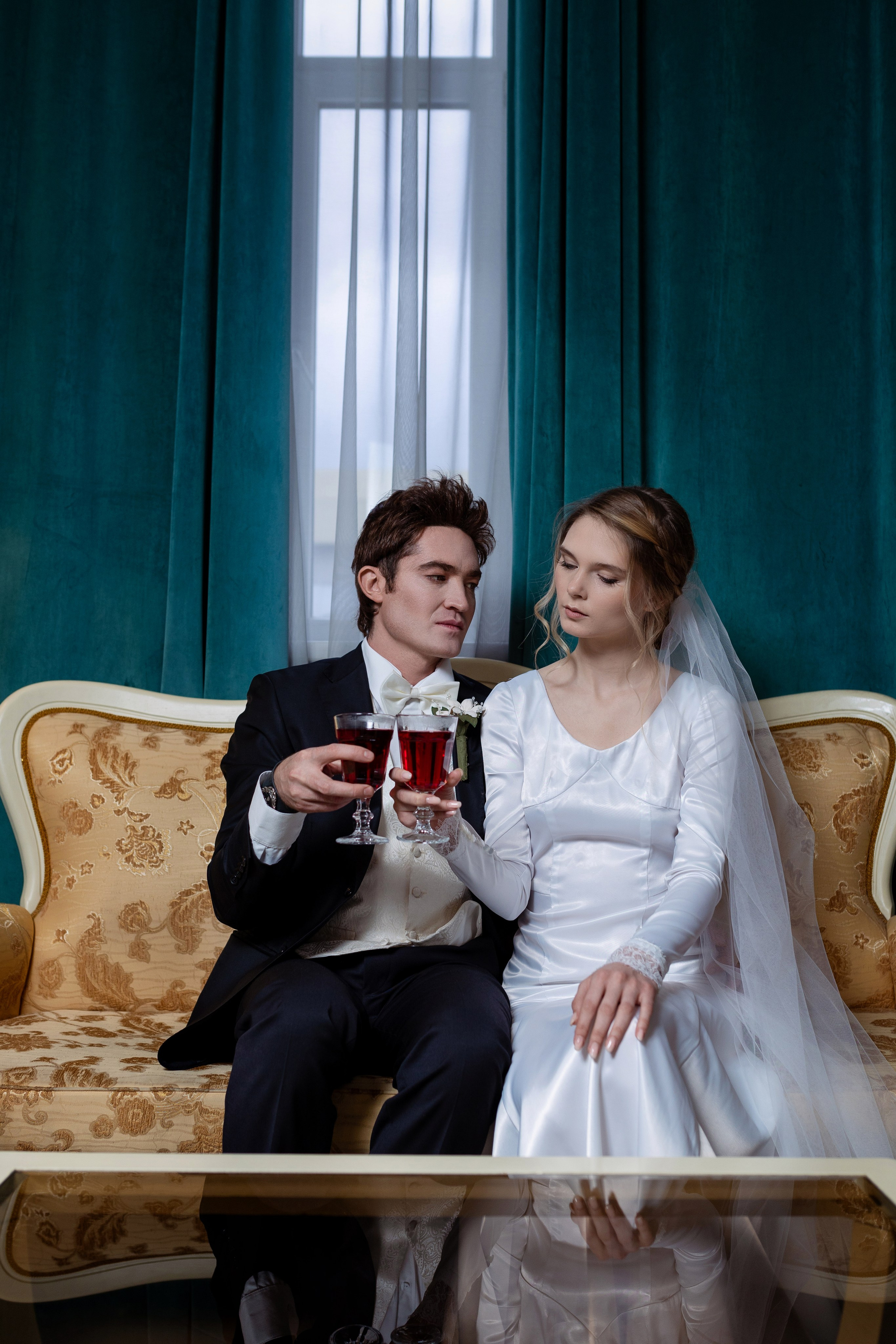 Жених и невеста сидят на диване с бокалами.