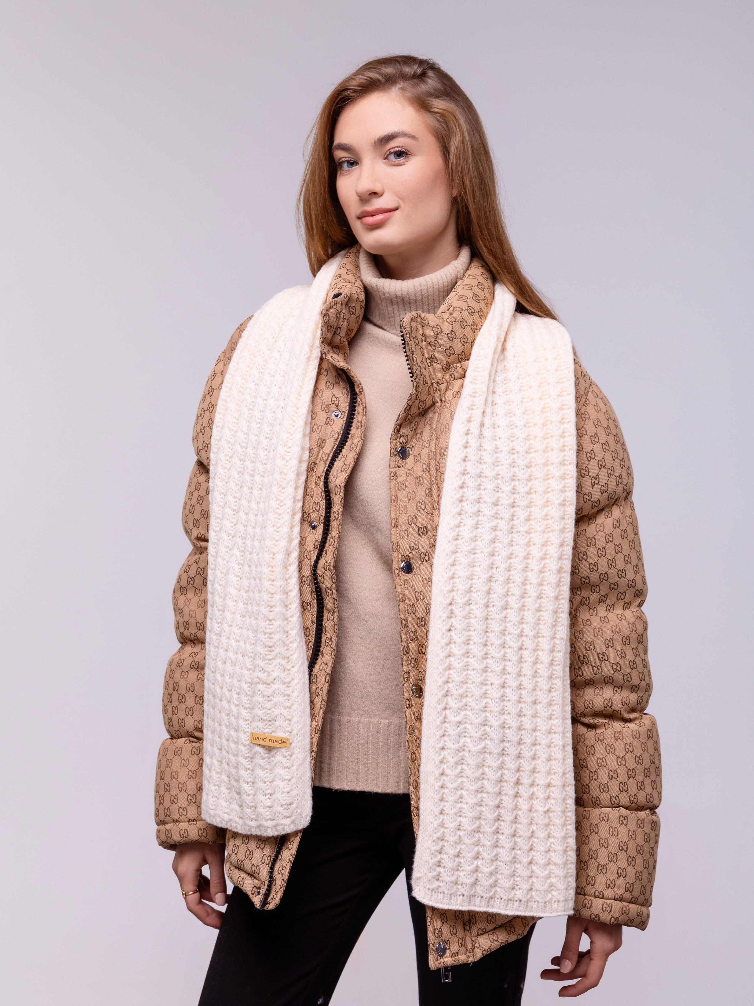 Белый шарф спущен поверх куртки девушки спереди.