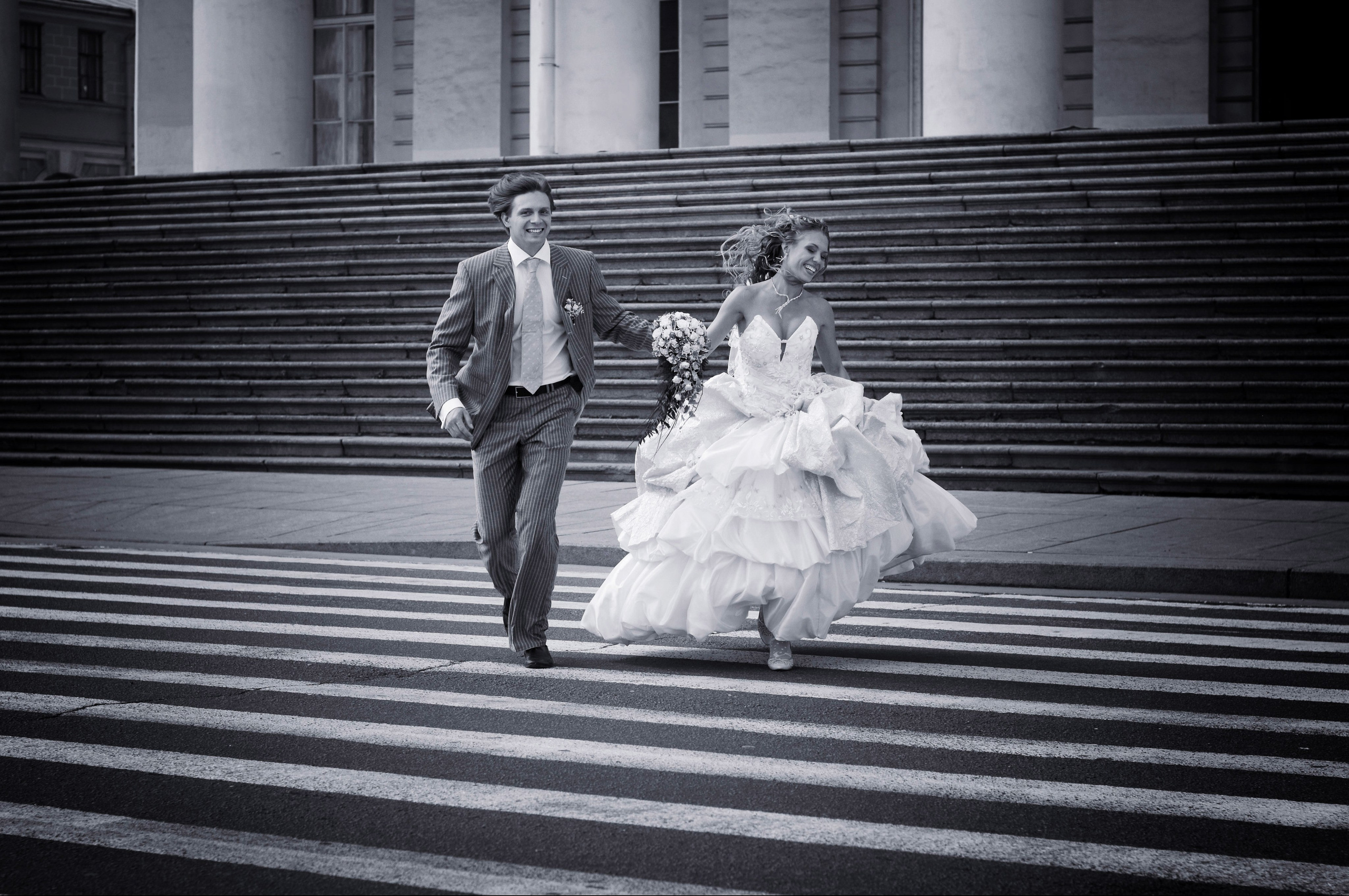 Бегущая пара молодоженов через пешеходный переход