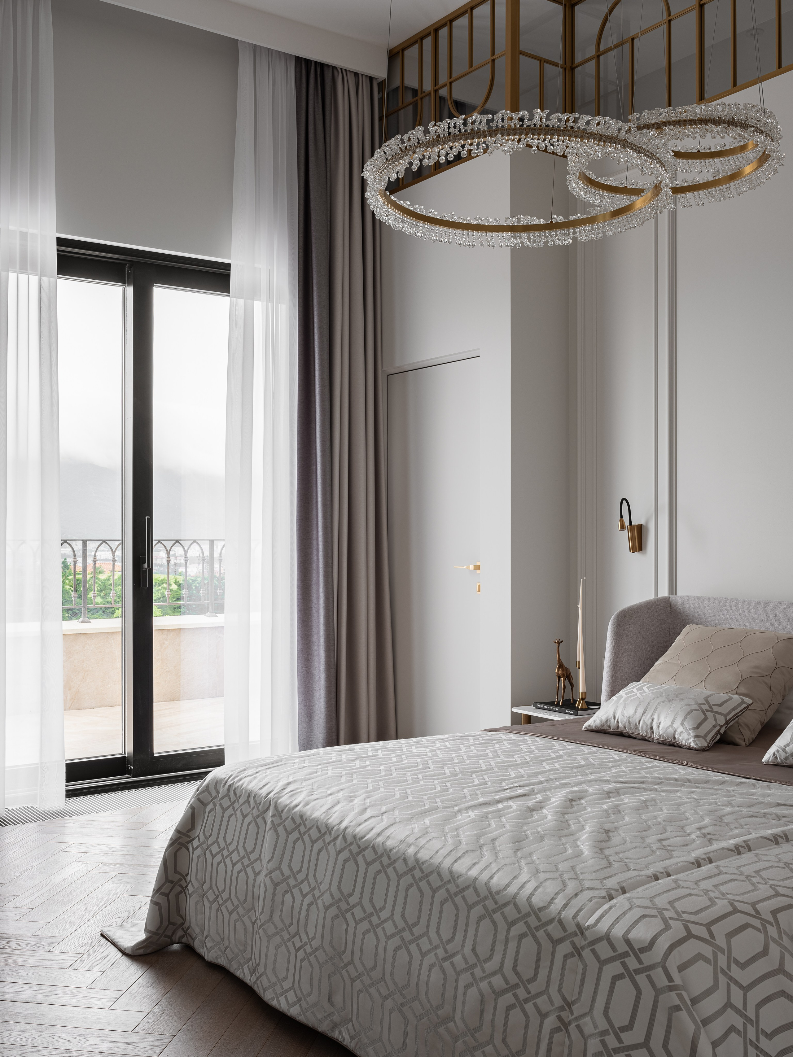 Элегантная спальня с высоким потолком: хрустальная люстра в виде колец, панорамное окно с серыми и белыми шторами, изысканное оформление стен и текстиля. Проект реализован дизайнером Василиссой Бачевой, стилист Наталья Якушева, фотограф Сергей Денисенко.