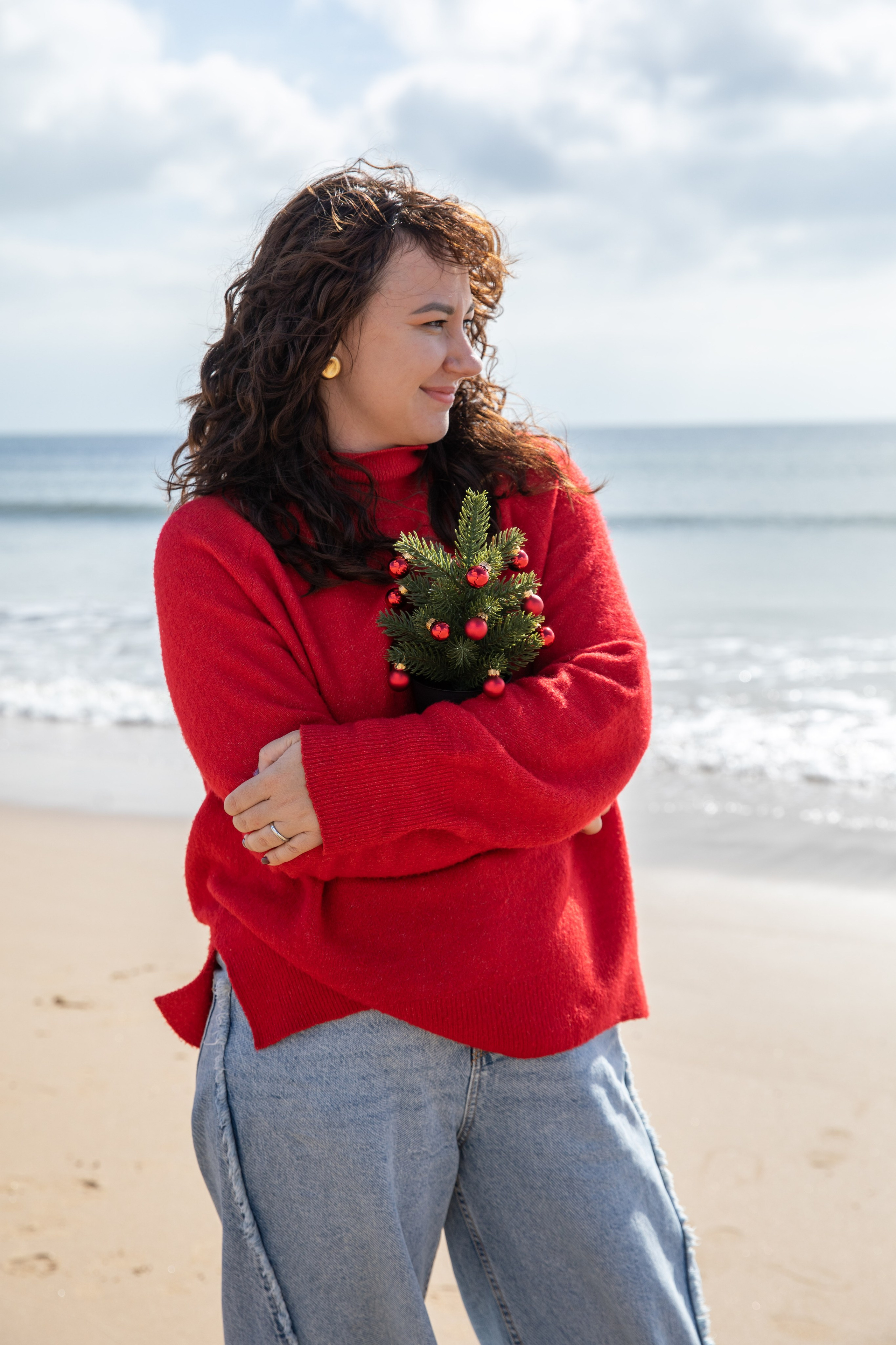 Mum looking out to the sea, lost in thought as the waves crash nearby