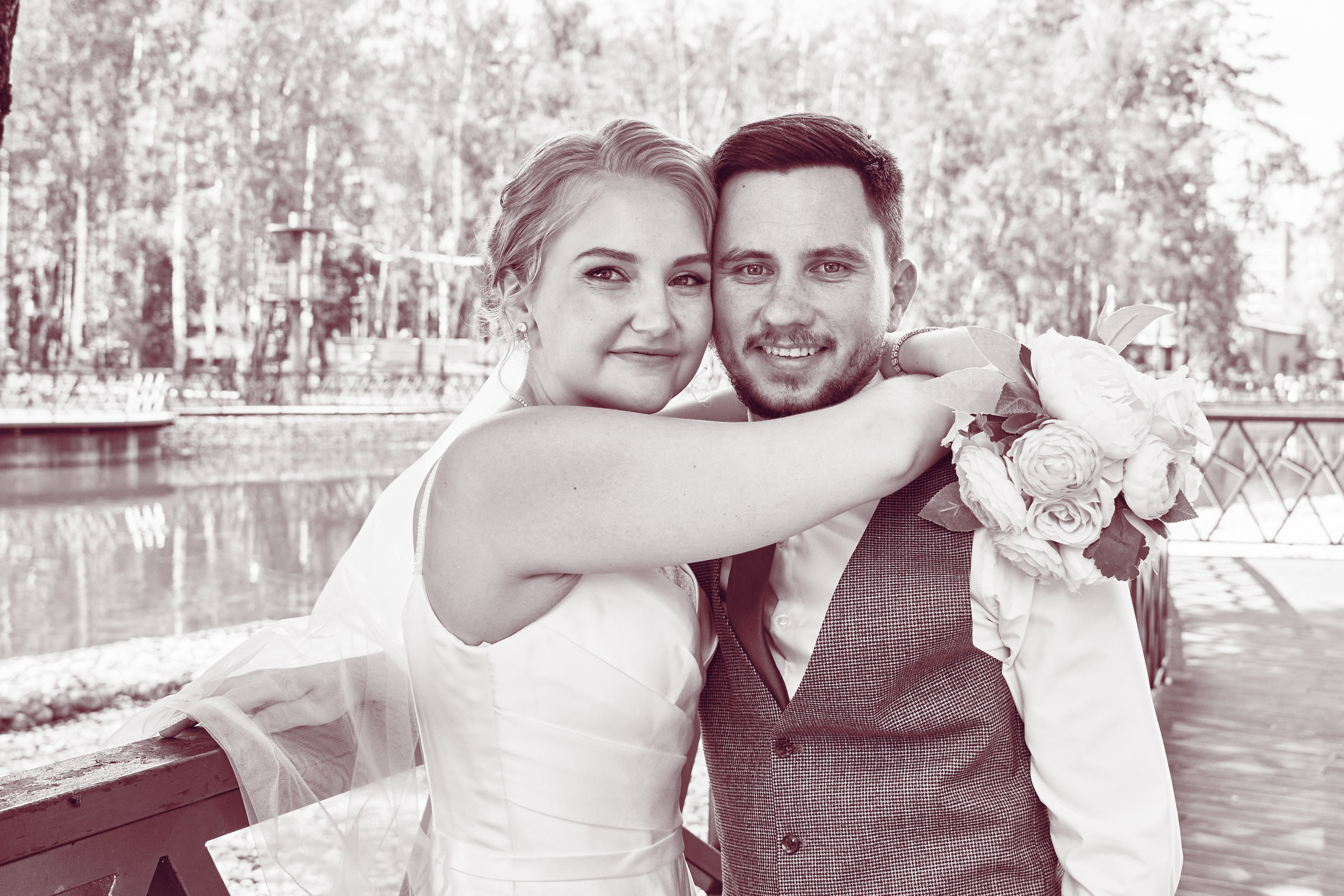 невеста обнимает жениха у воды в парке