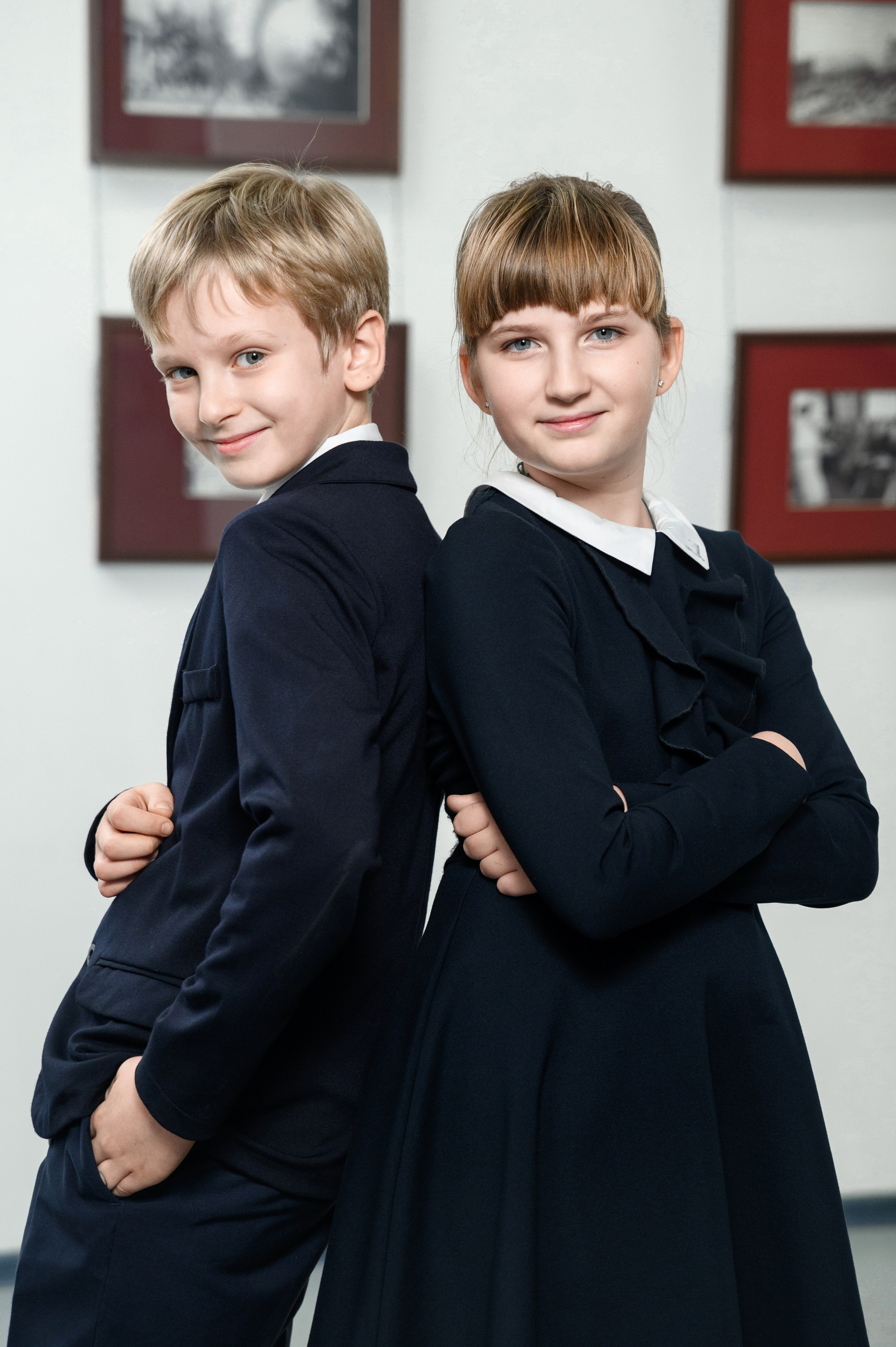 Два ученика в школьной форме стоят спиной друг к другу