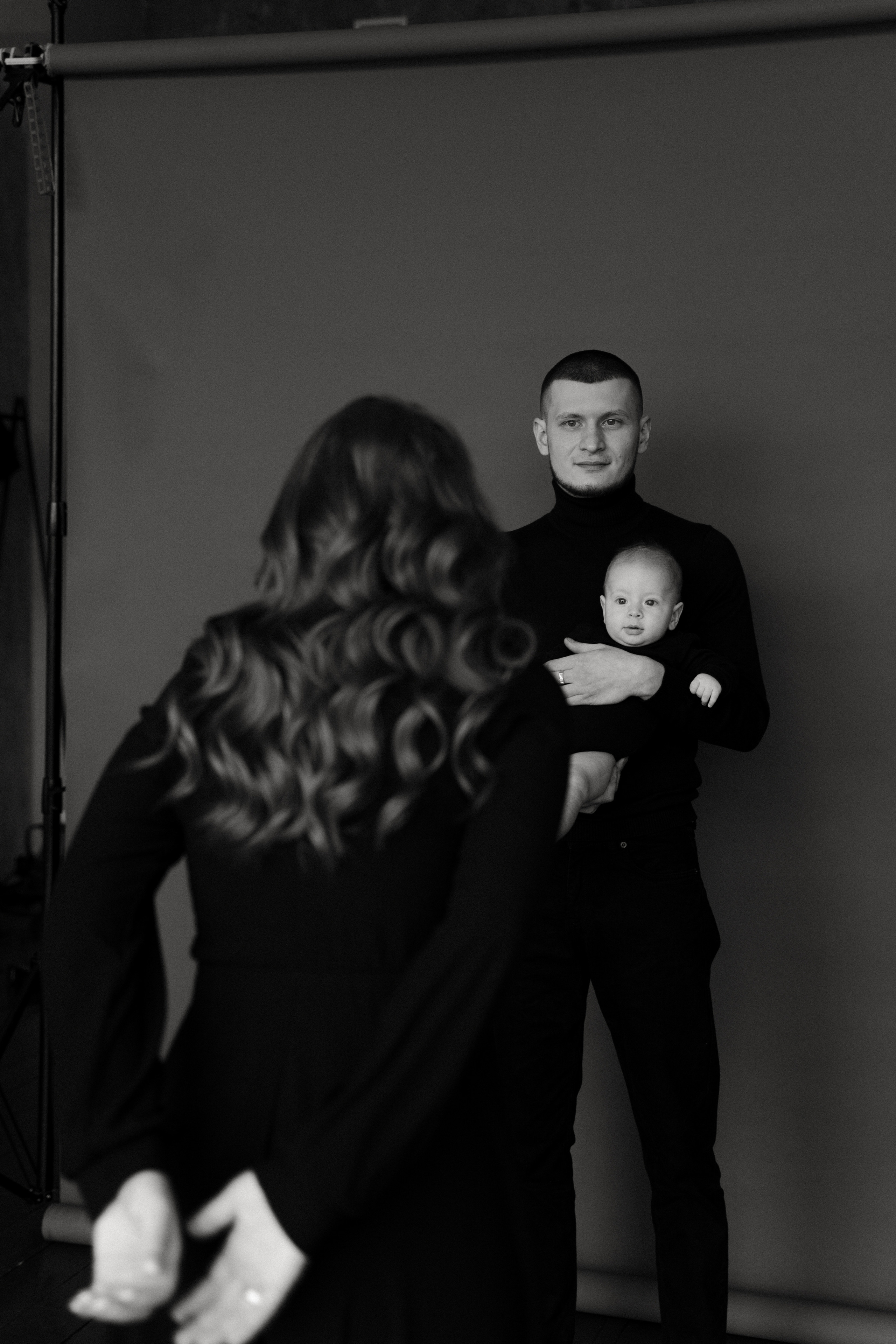 Мама развлекает ребенка на семейной фотосессии, отец держит ребенка на руках