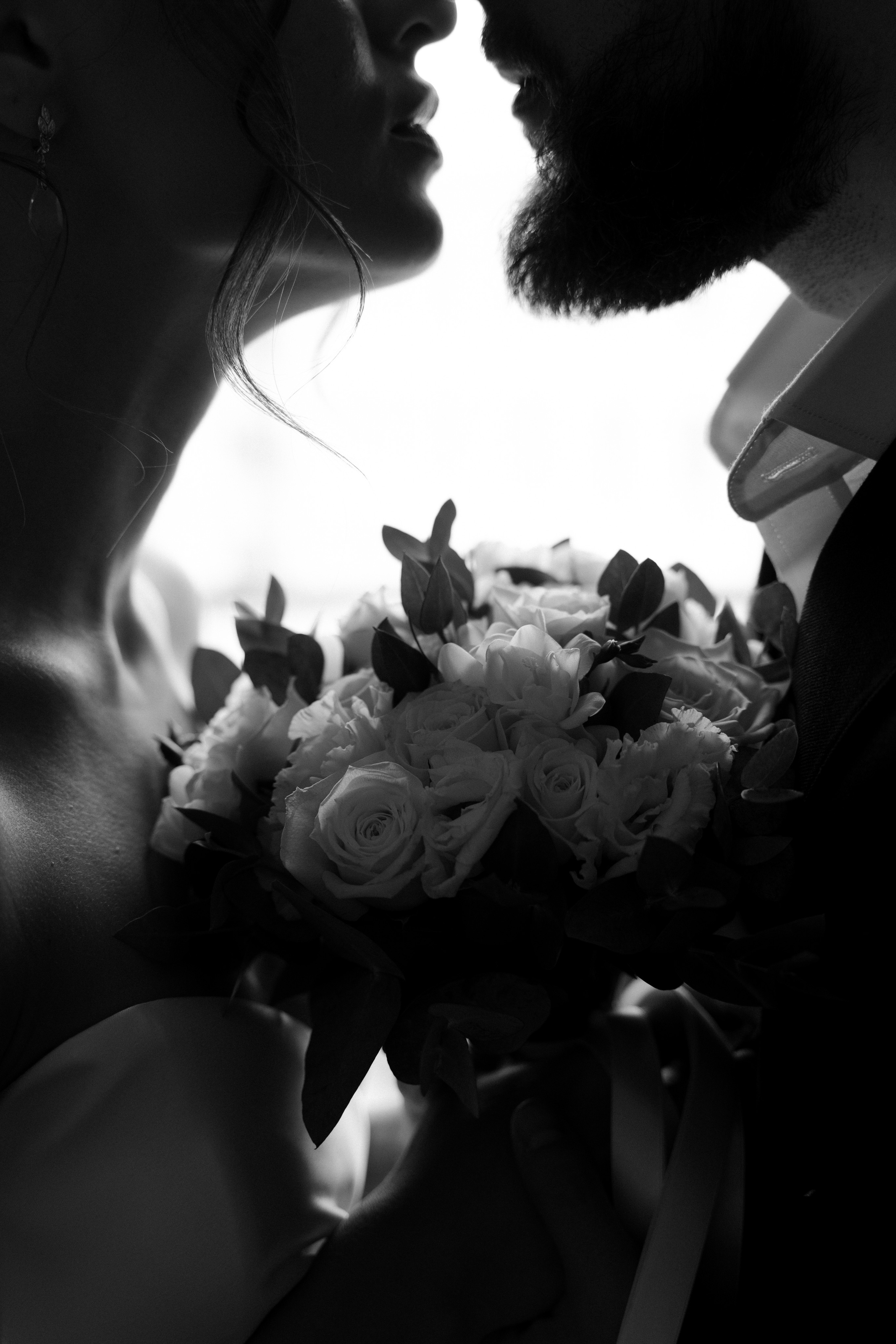 Черно-белый близкий снимок пары с букетом невесты у окна