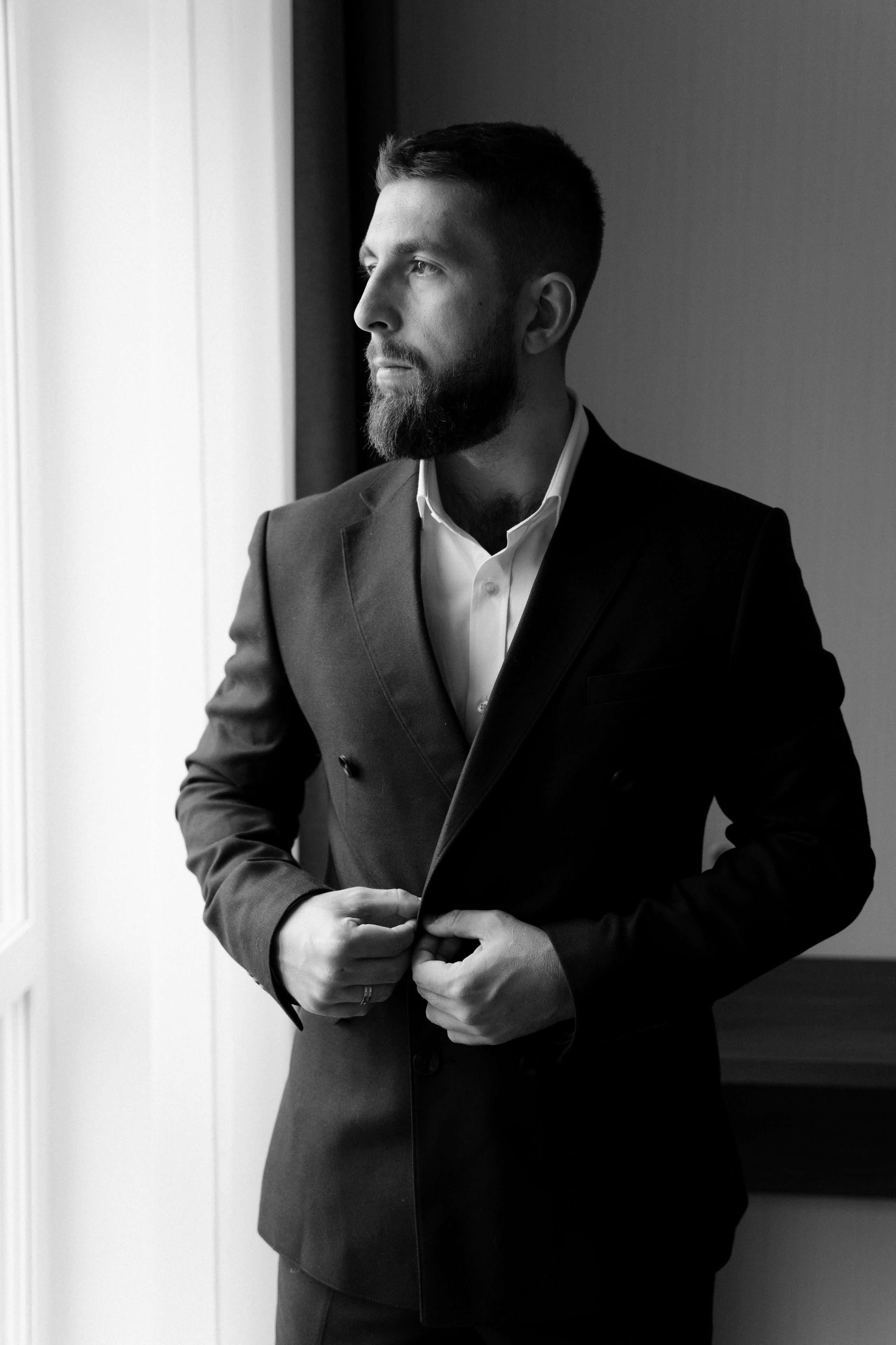 Портрет жениха черно-белый у окна в отеле