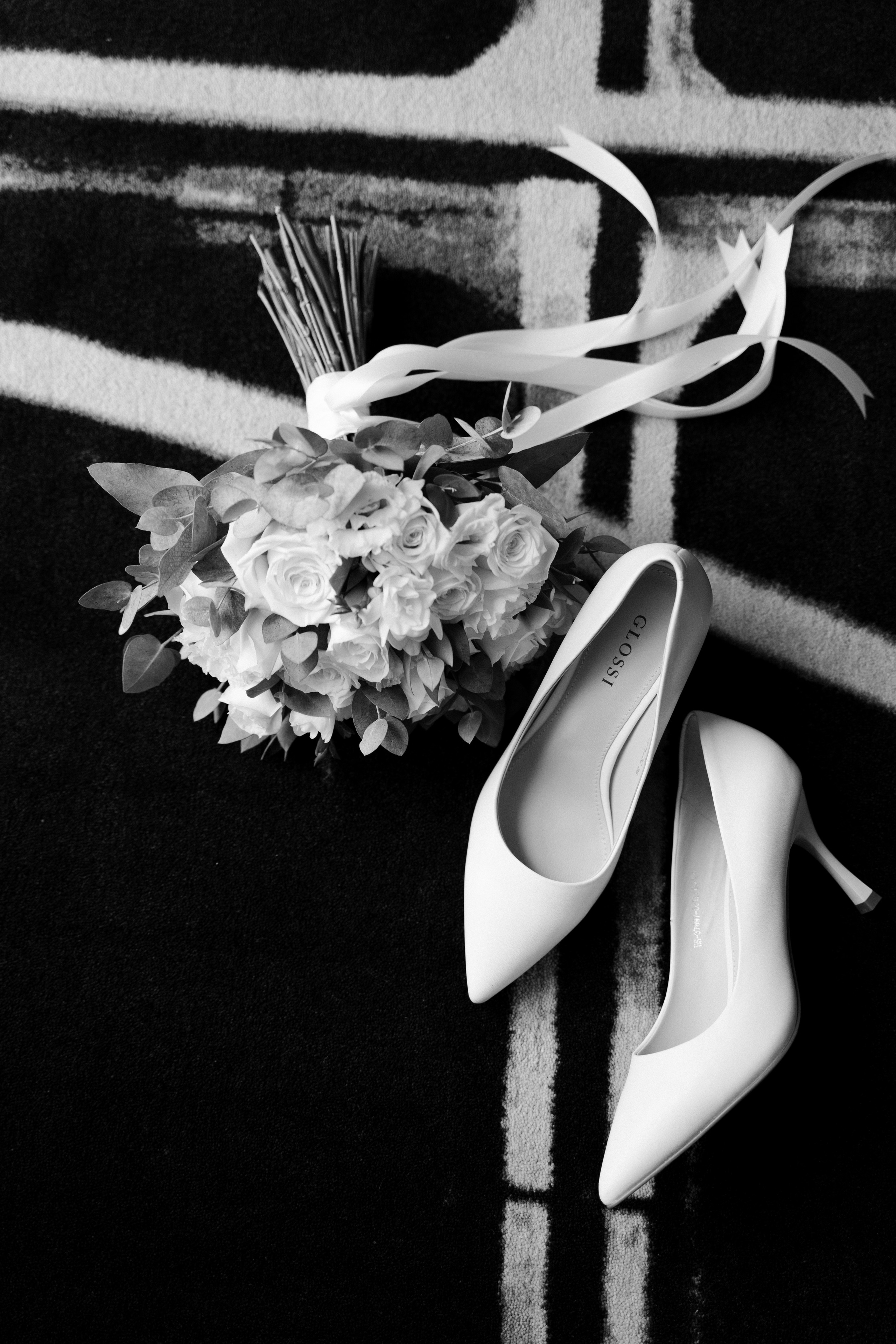 Сборы невесты в отеле, букет цветов и белые туфли на полу в гостинице.