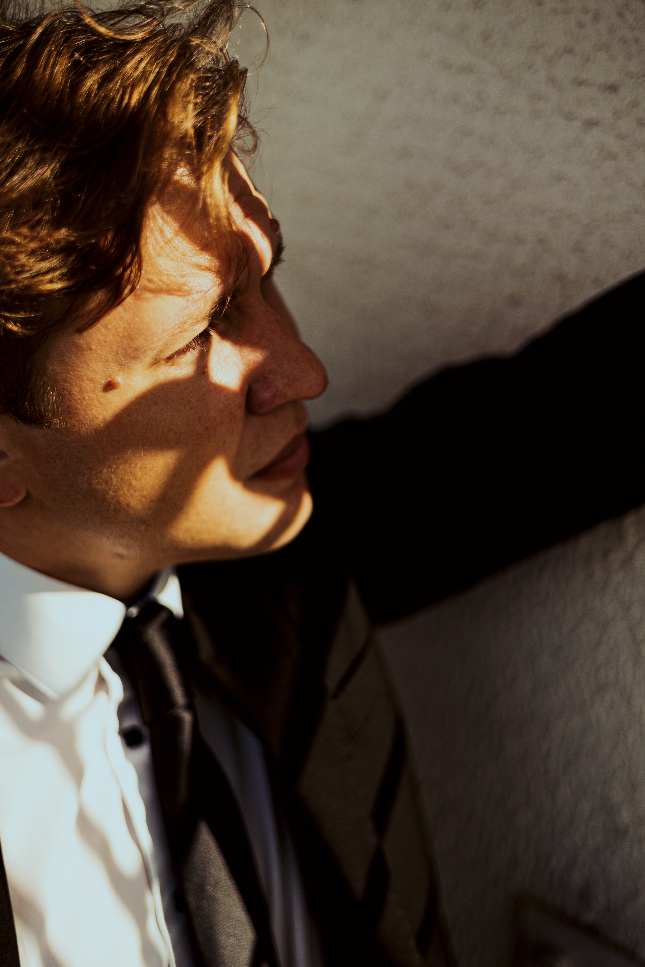 Молодой человек в костюме заслоняется от солнца