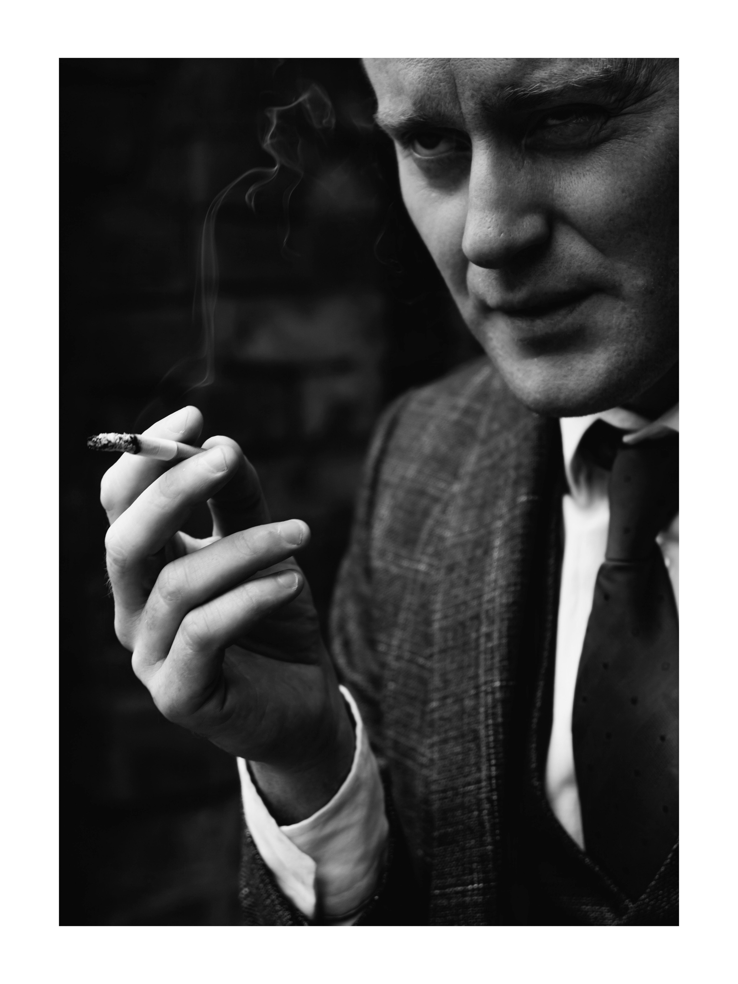 мужчина щурится хмурится и курит