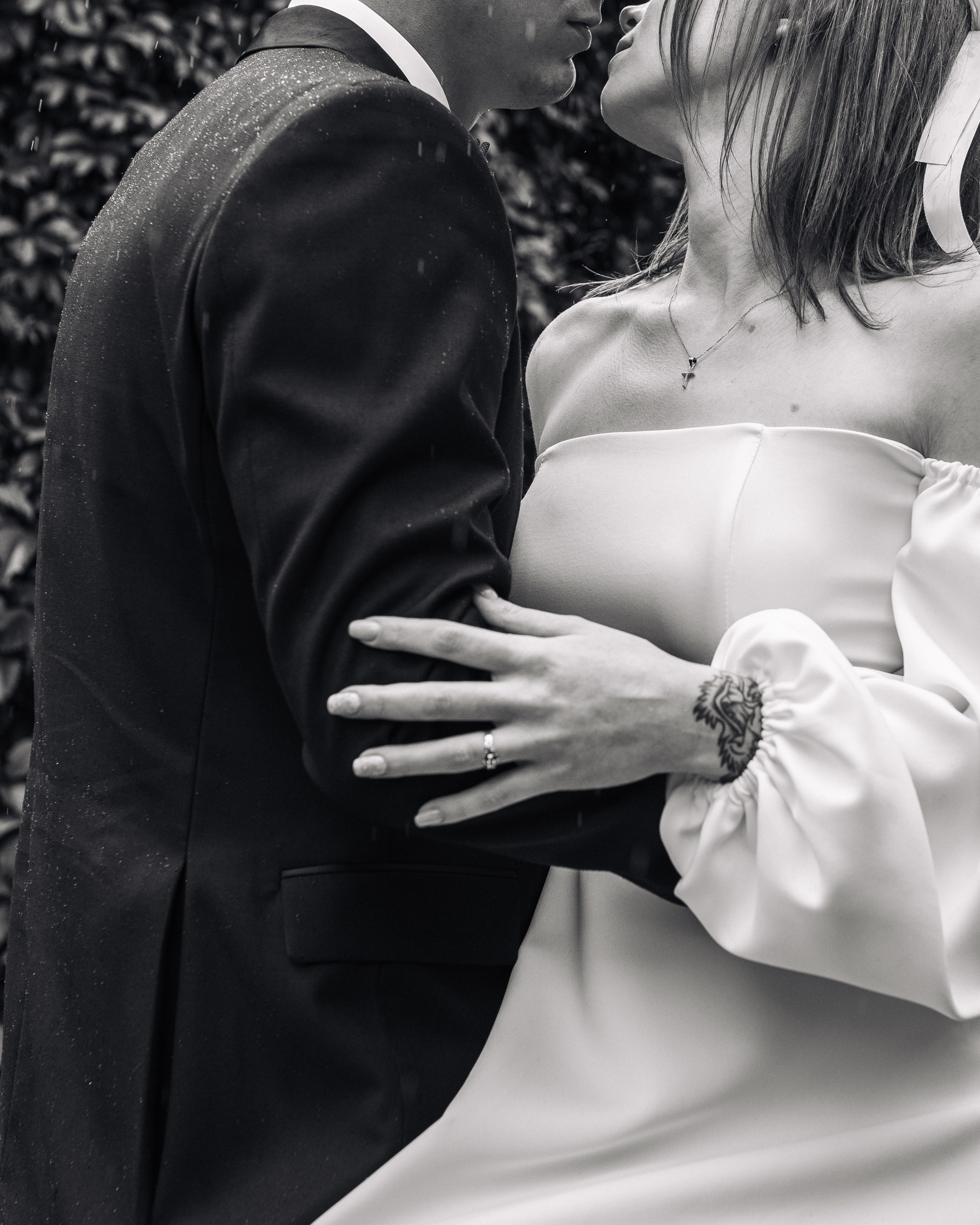 Крупный кадр жениха и невесты в момент поцелуя под дождём 