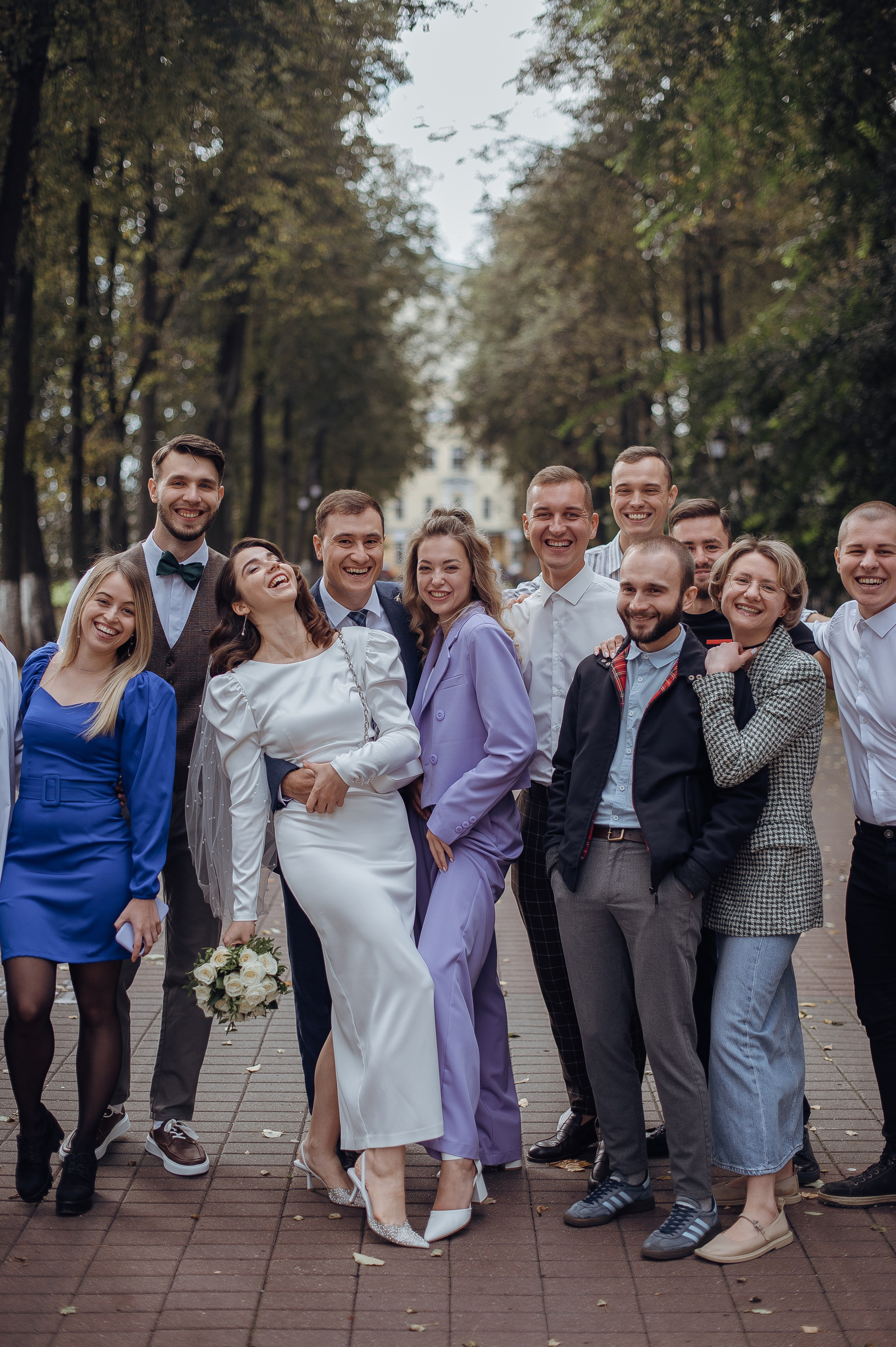 Друзья молодлженов смеются на гурпповой фотогарфиии