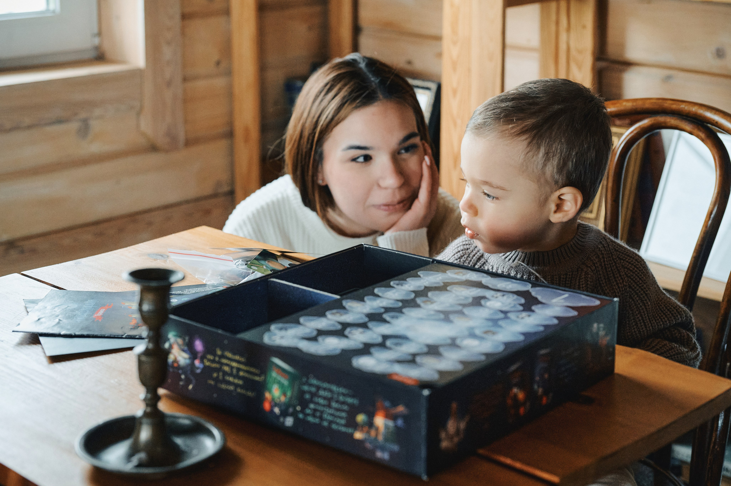 ребёнок и мама играют в настольную игру в деревянном доме