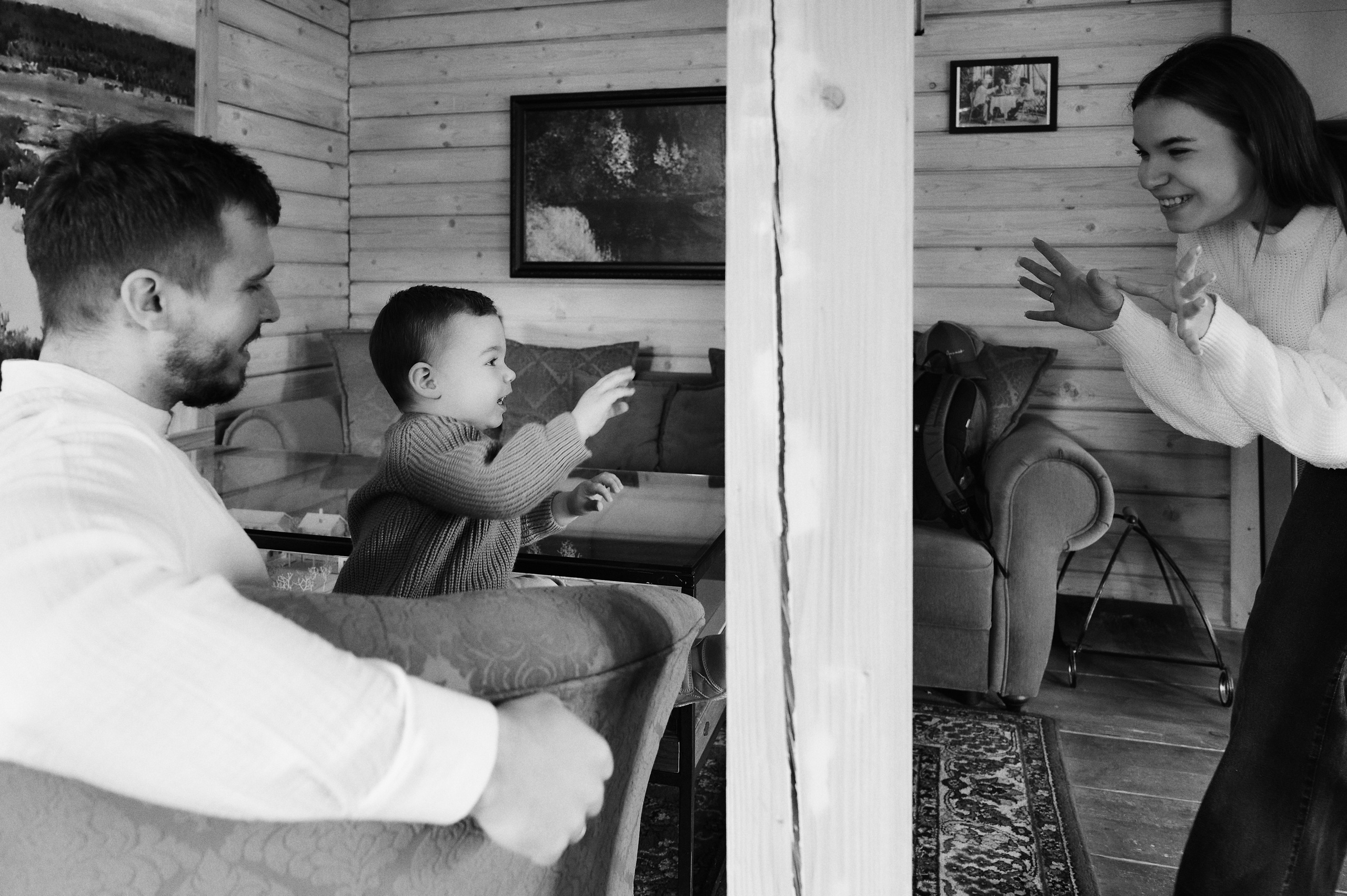 семейная сцена в интерьере, мама играет с ребёнком, папа улыбается, уютный деревянный дом