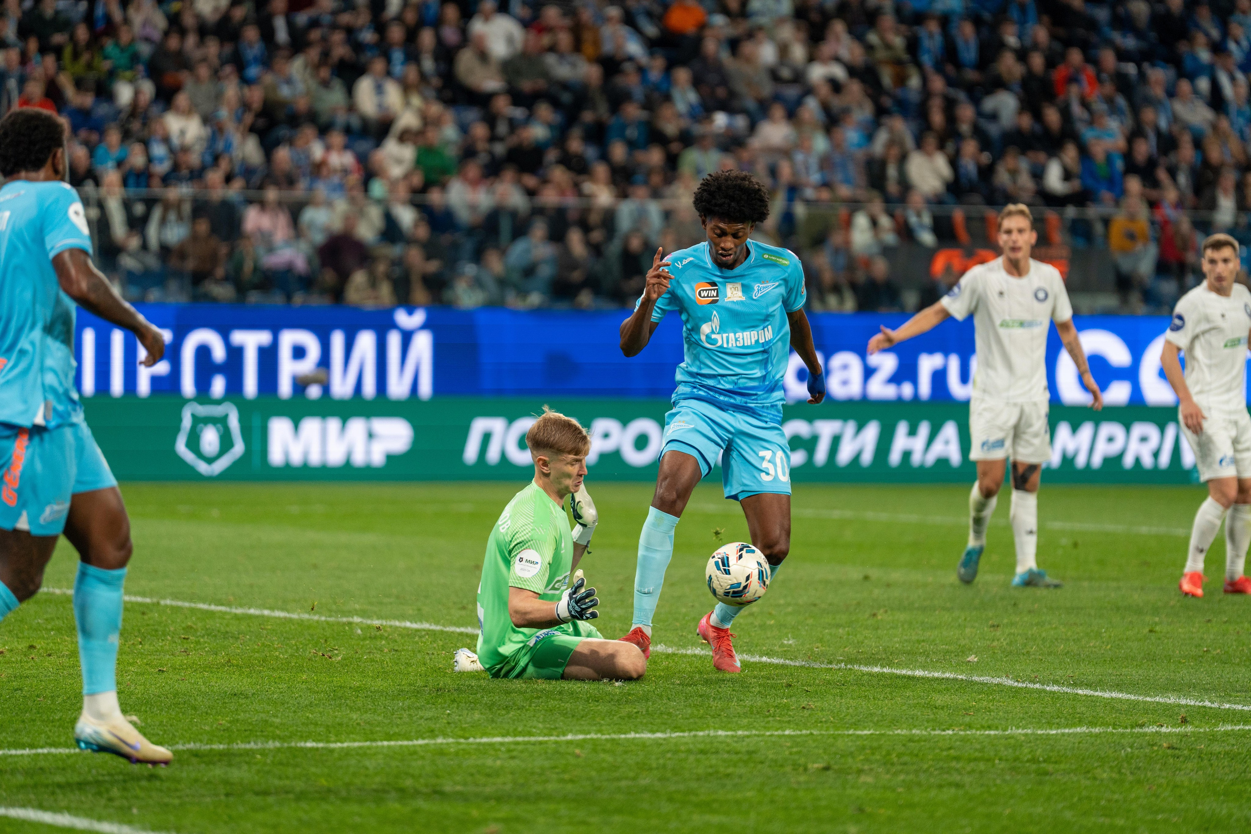 Игрок Зенита в голубой форме обходит вратаря Оренбурга на Газпром Арене — репортажный спортивный фотограф Санкт-Петербург