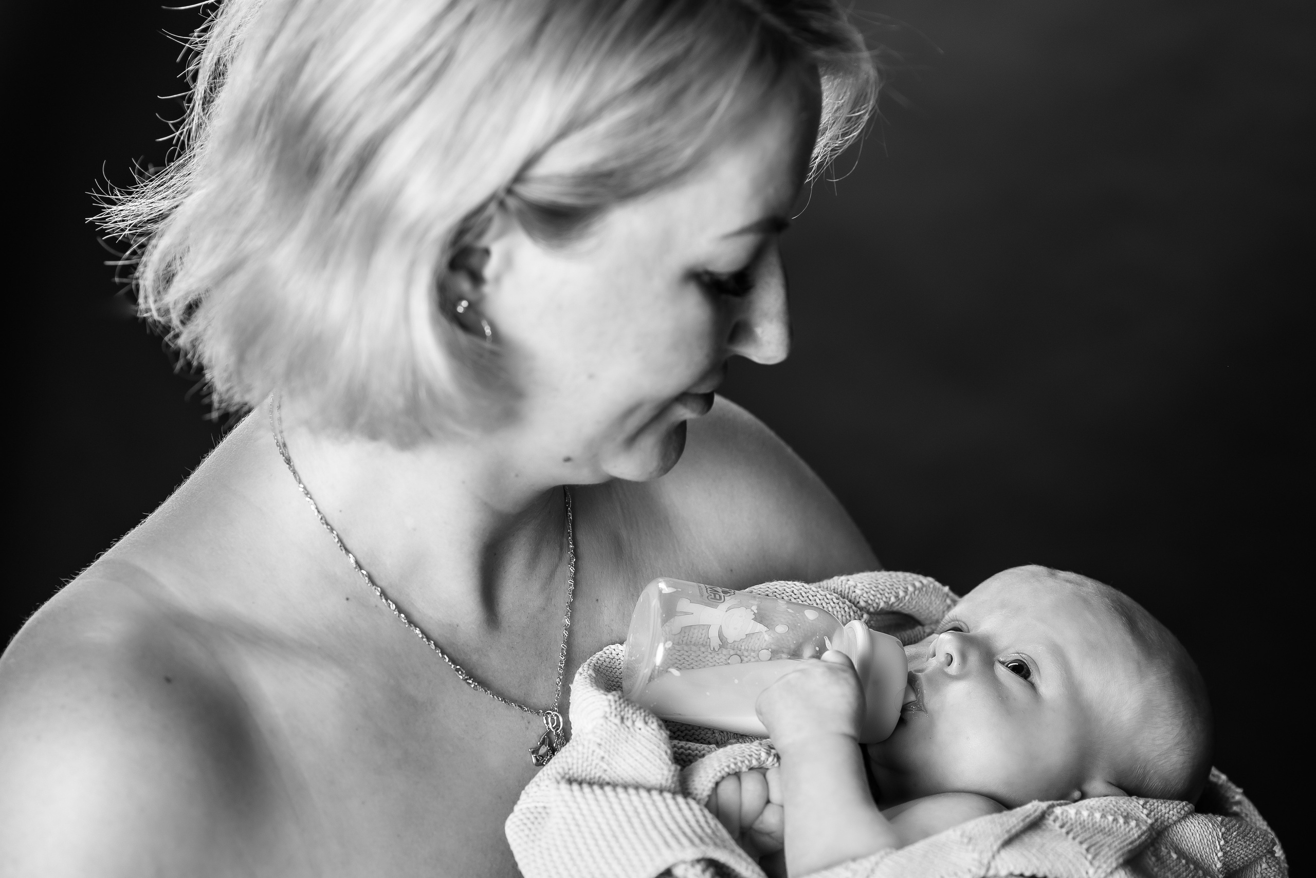 черно-белое фото мама держит на руках малыша с бутылочкой