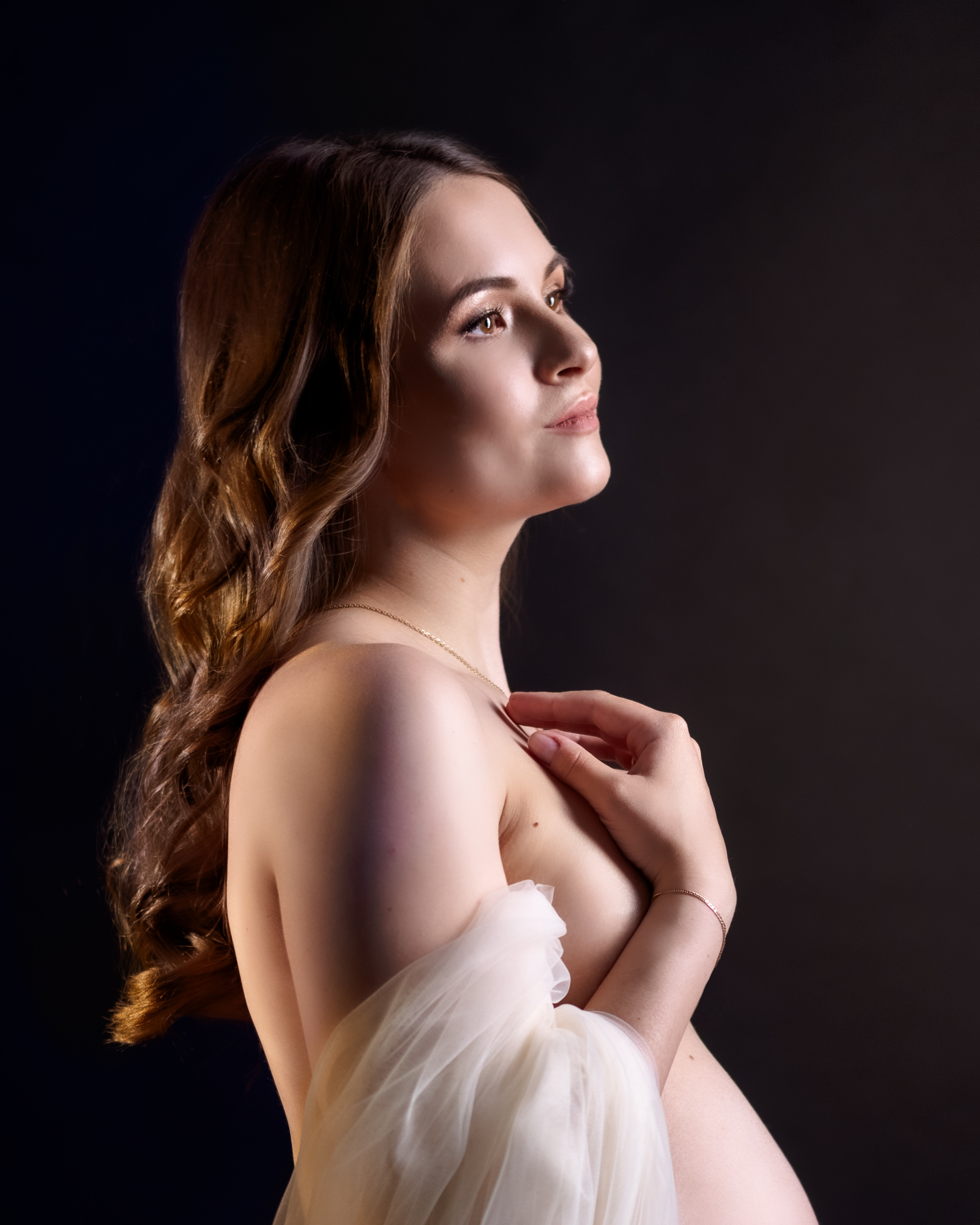 обнаженная беременная женщина с прозрачной легкой тканью на черном фоне крупный портрет