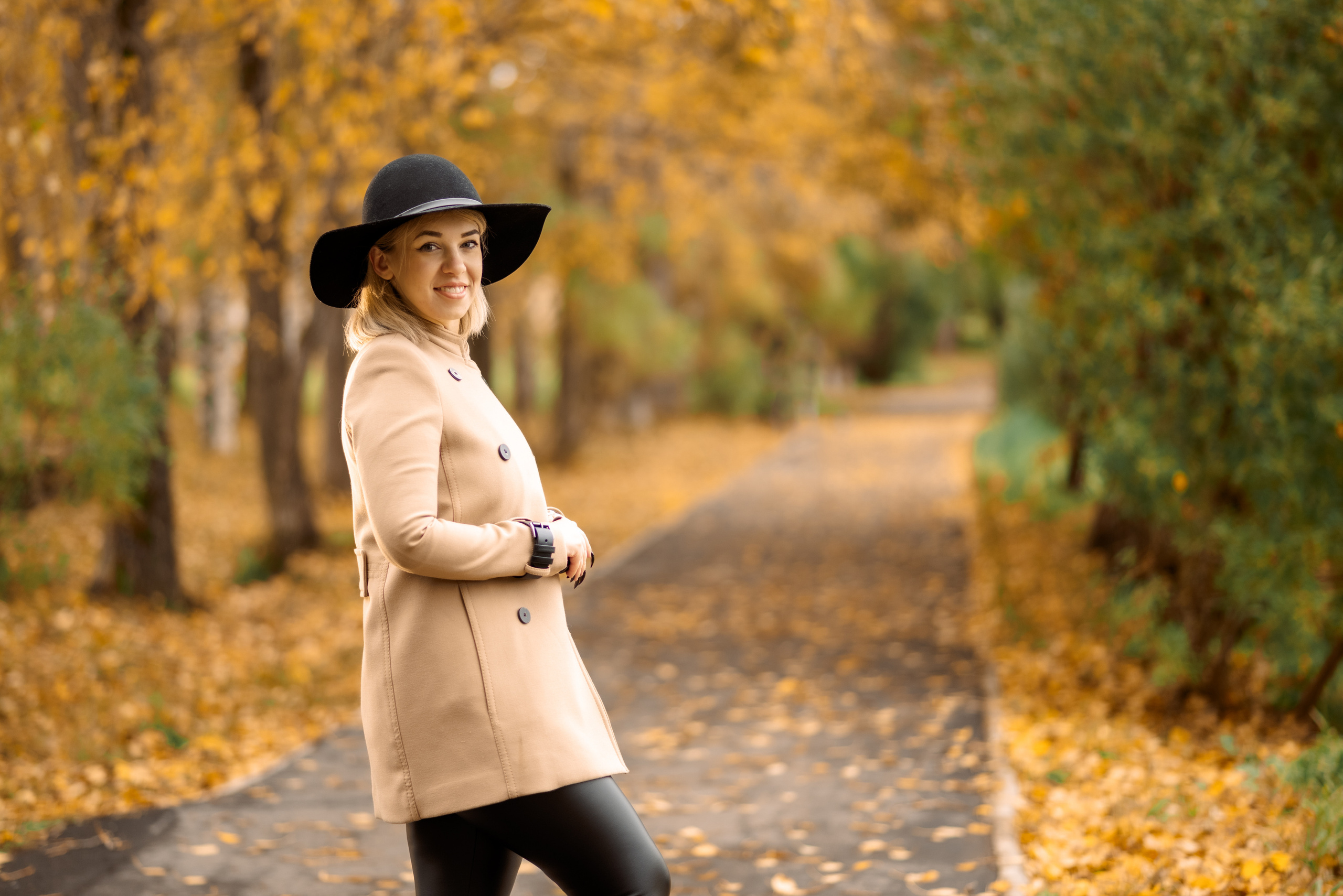 девушка в шляпе на прогулке в осеннем парке обернулась назад