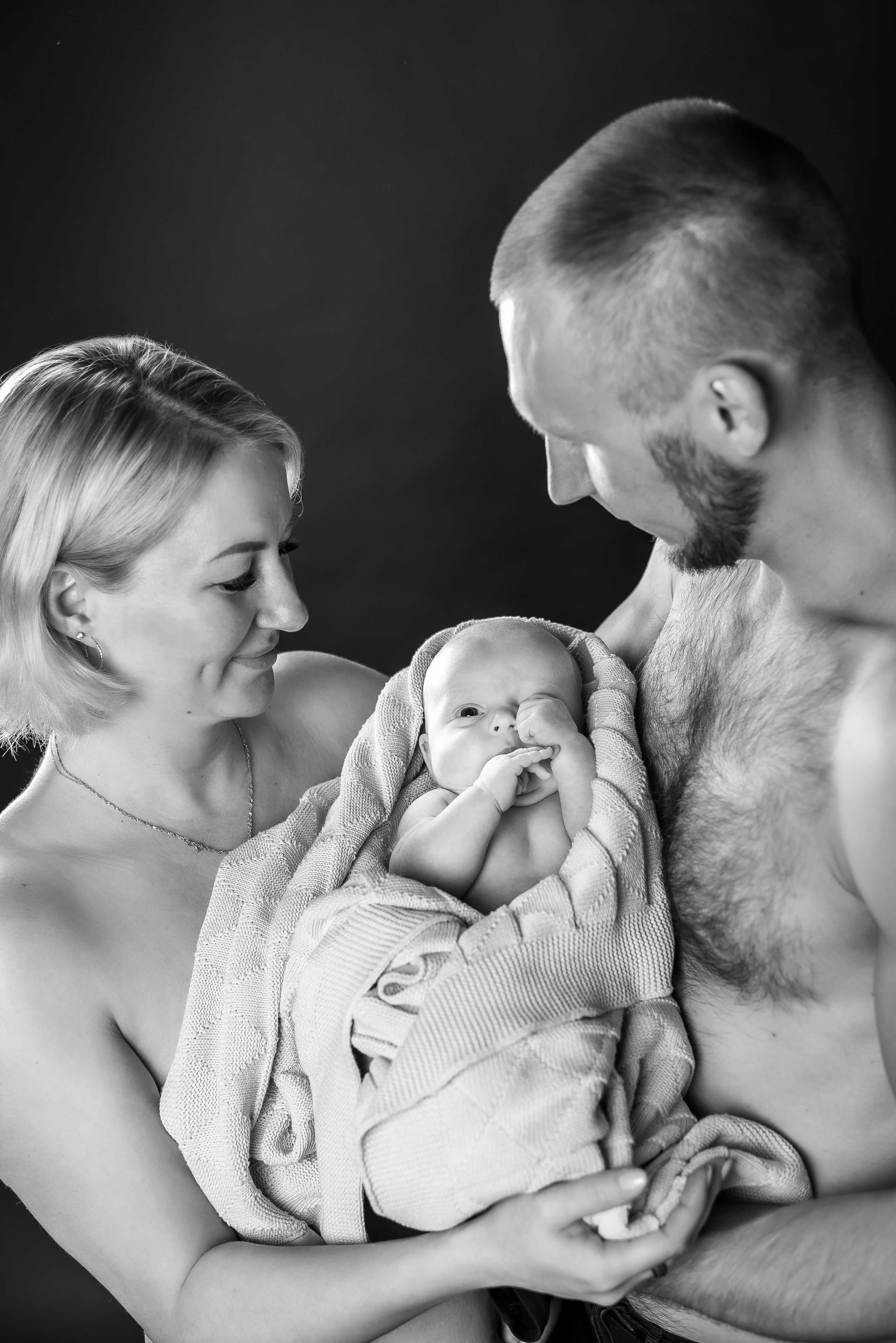 черно-белое фото папа и мама обнимают малыша в одеяльце