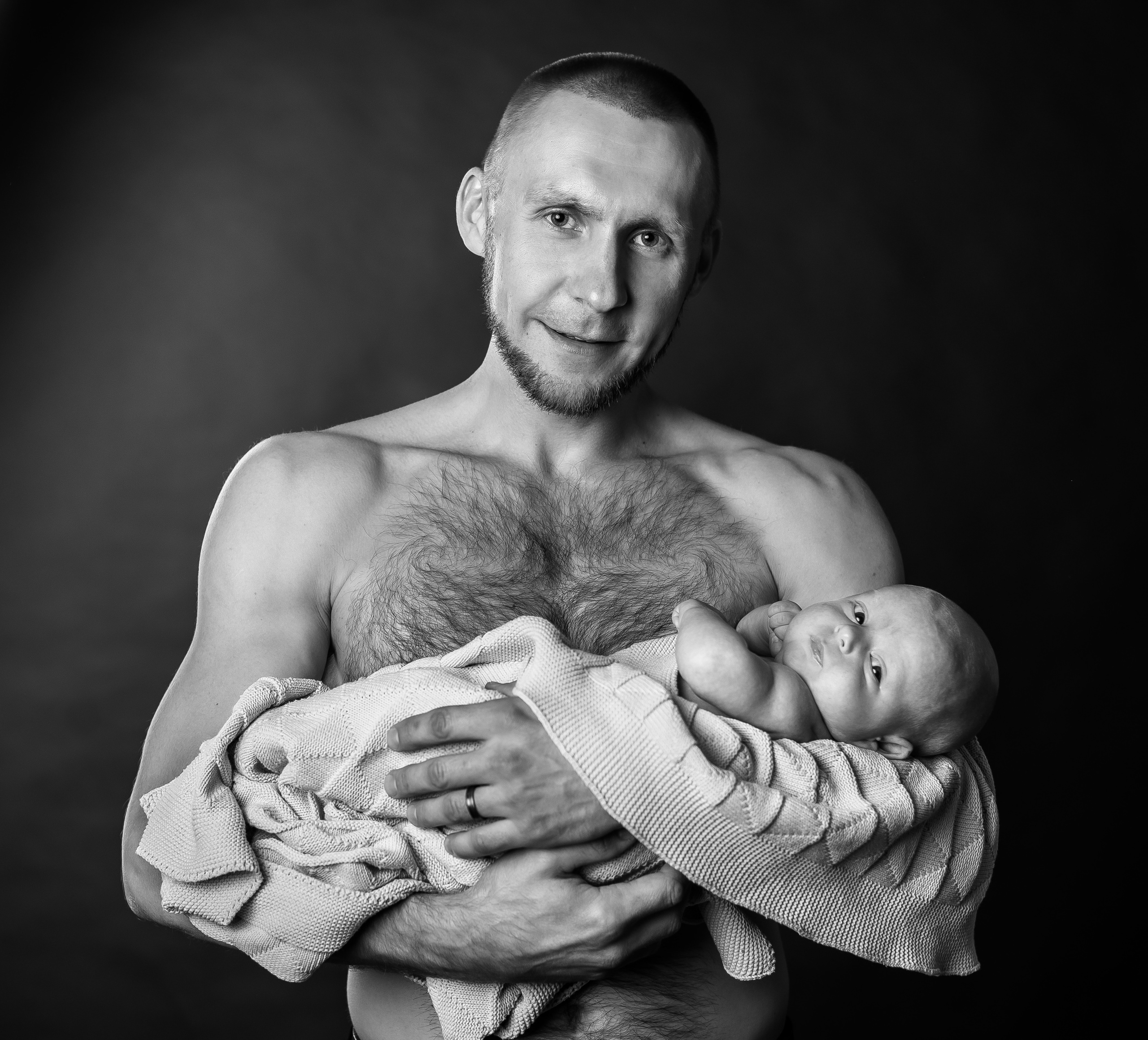 черно-белое фото папа с голым торсом держит малыша в одеяльце на руках