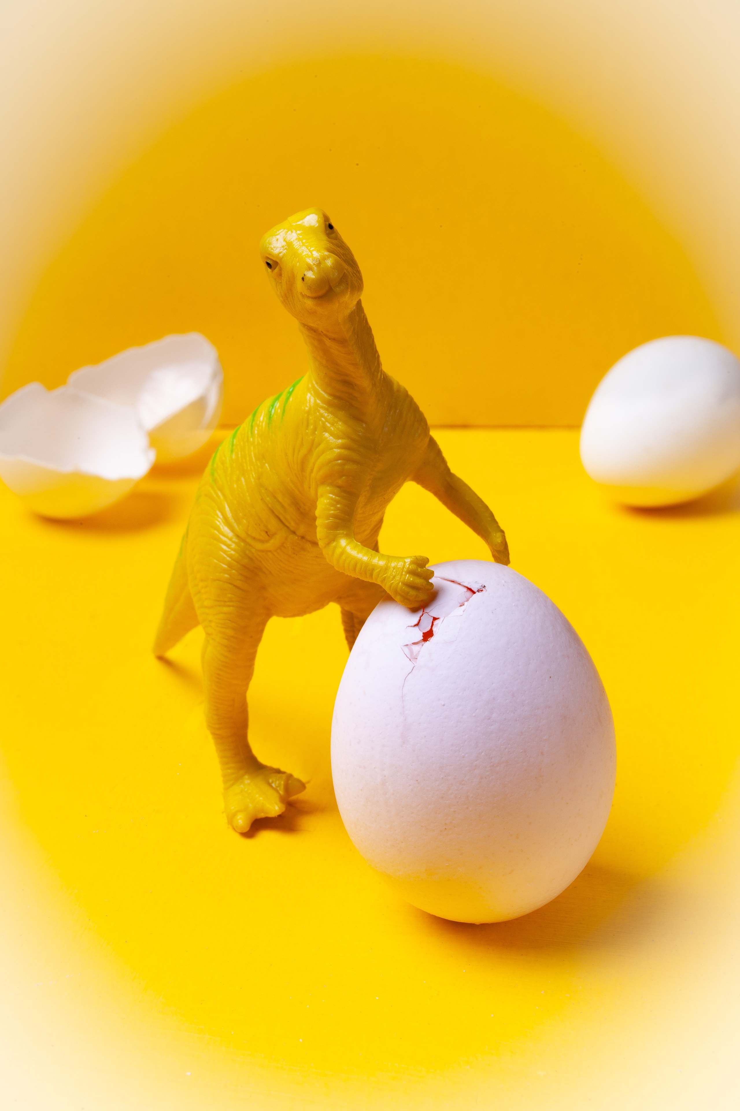 Милый динозаврик на желтом фоне с белым яйцом 