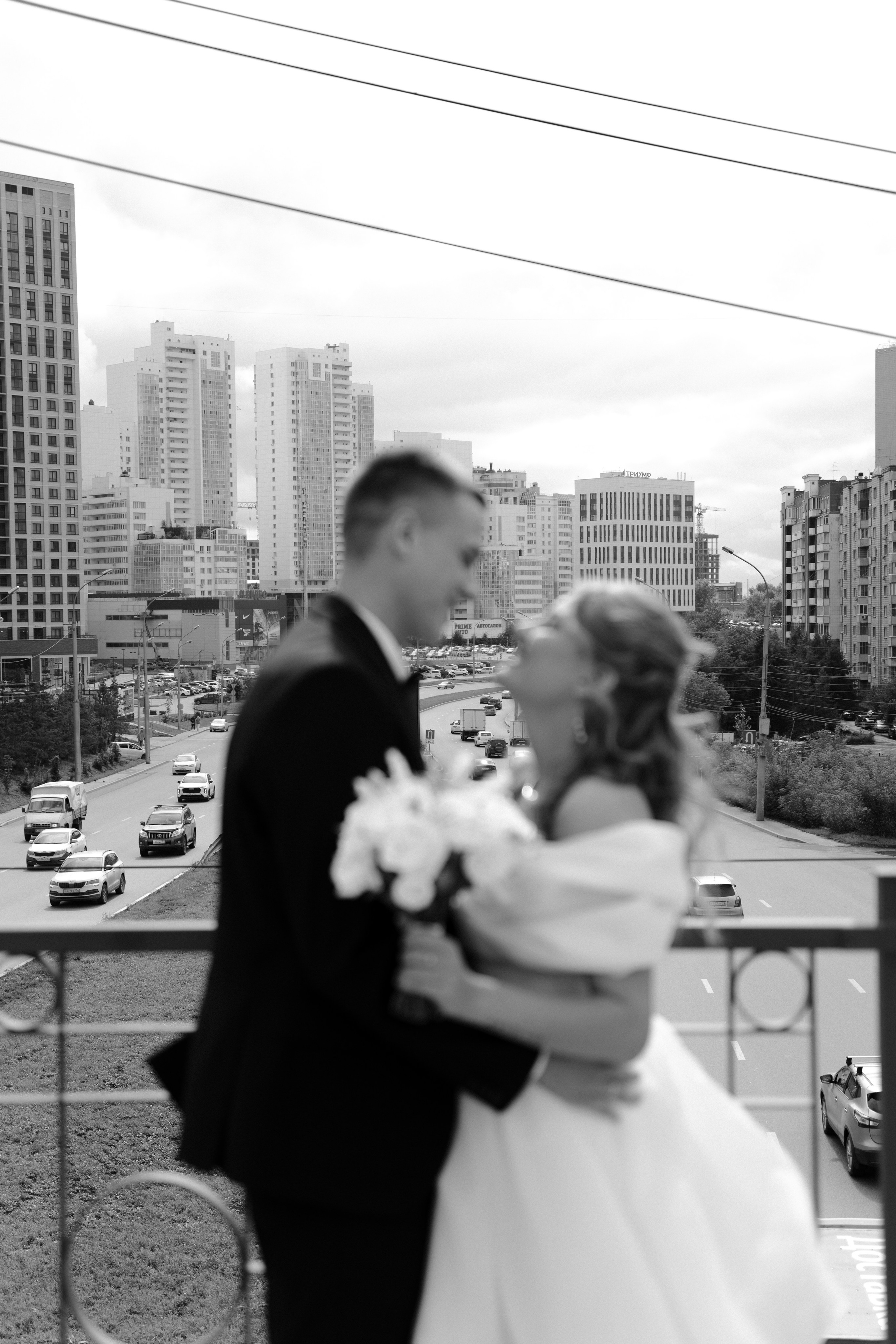 Пара стоит на мосту и позади едут машины