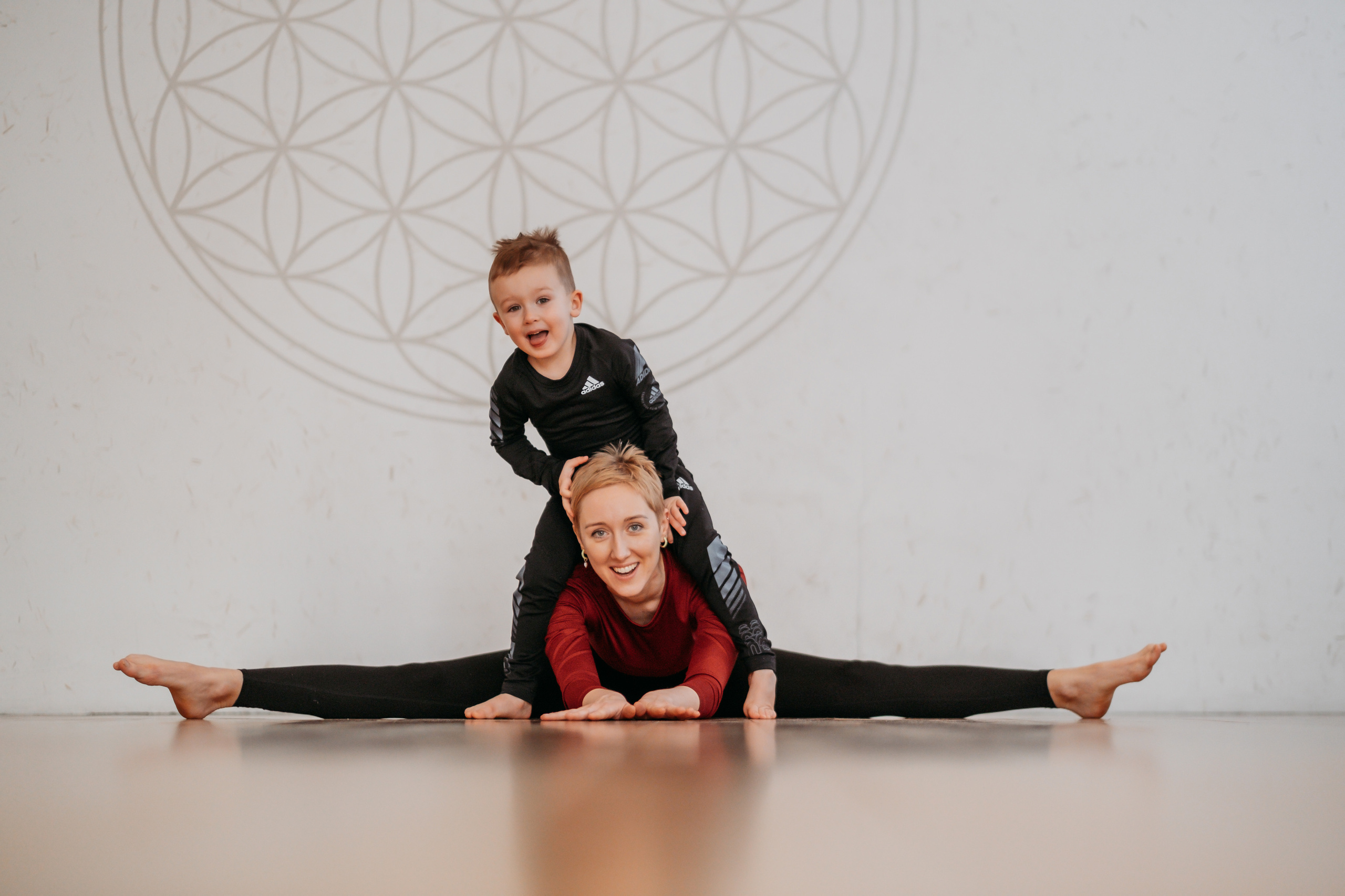 Девушка сидит на шпагате, ребенок сидит у нее на спине