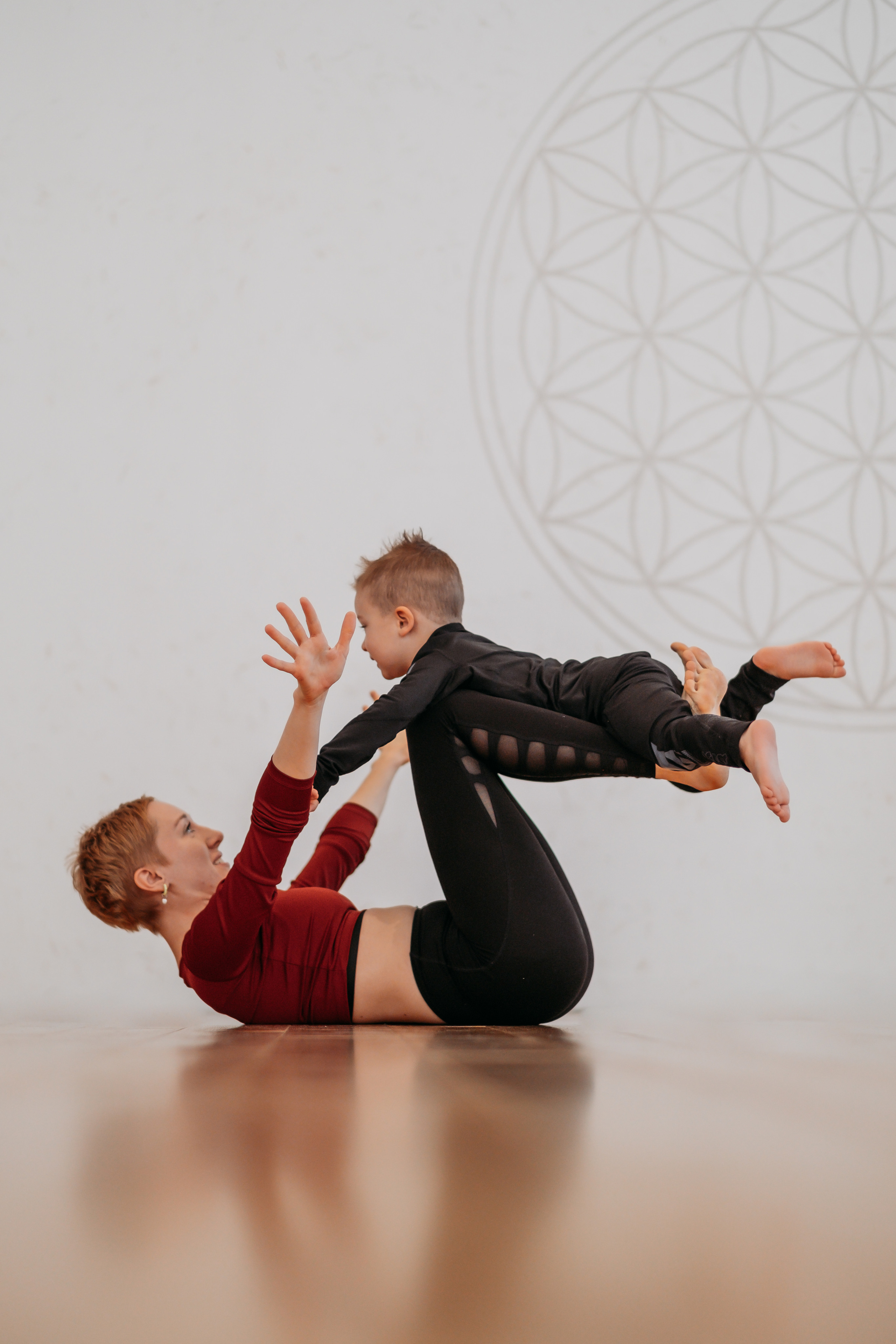 Акройога мамы и сына на фоне цветка жизни