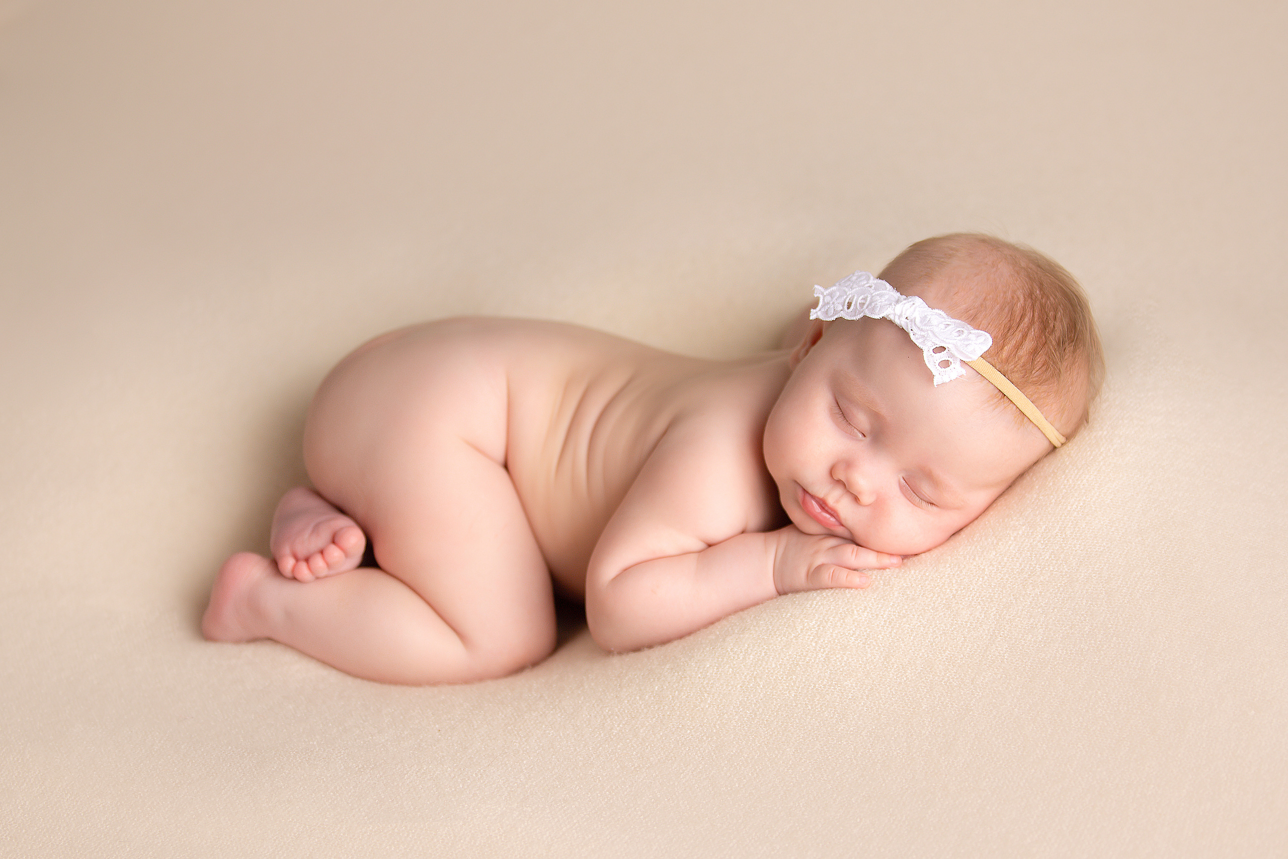 фотосессия малыши до года девочка лежит на животе в ободочке на светлом фоне