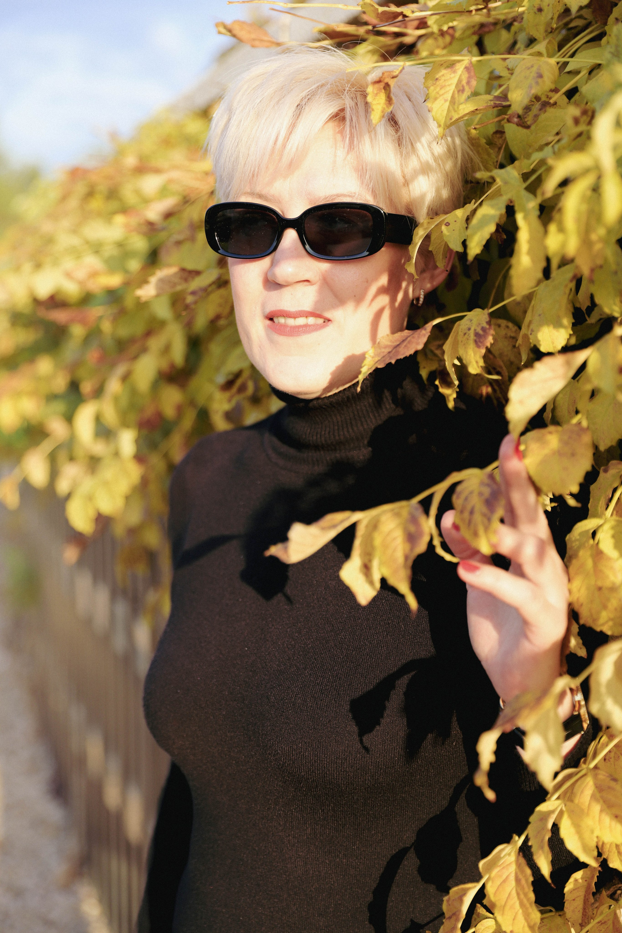 Девушка в стильном свитере и темных очках наслаждается свежим воздухом и красотой парка Краснодар.