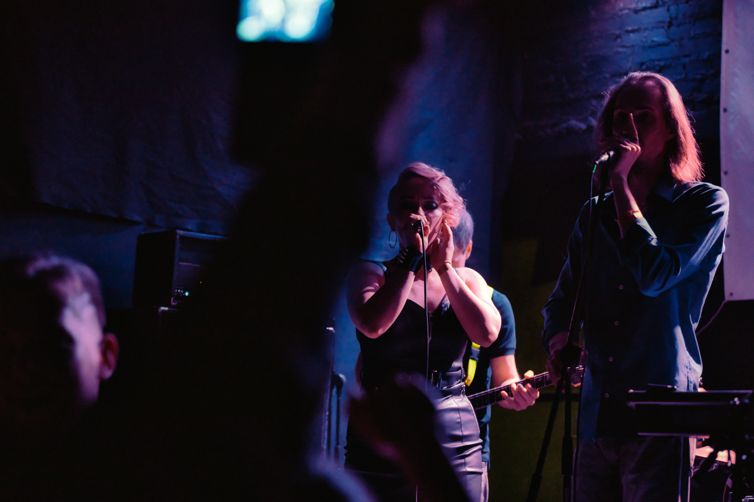 Дуэт вокалистов - мужской и женский голос - поют вместе на сцене с синим сценическим светом, эмоциональное выступление, концертная фотография