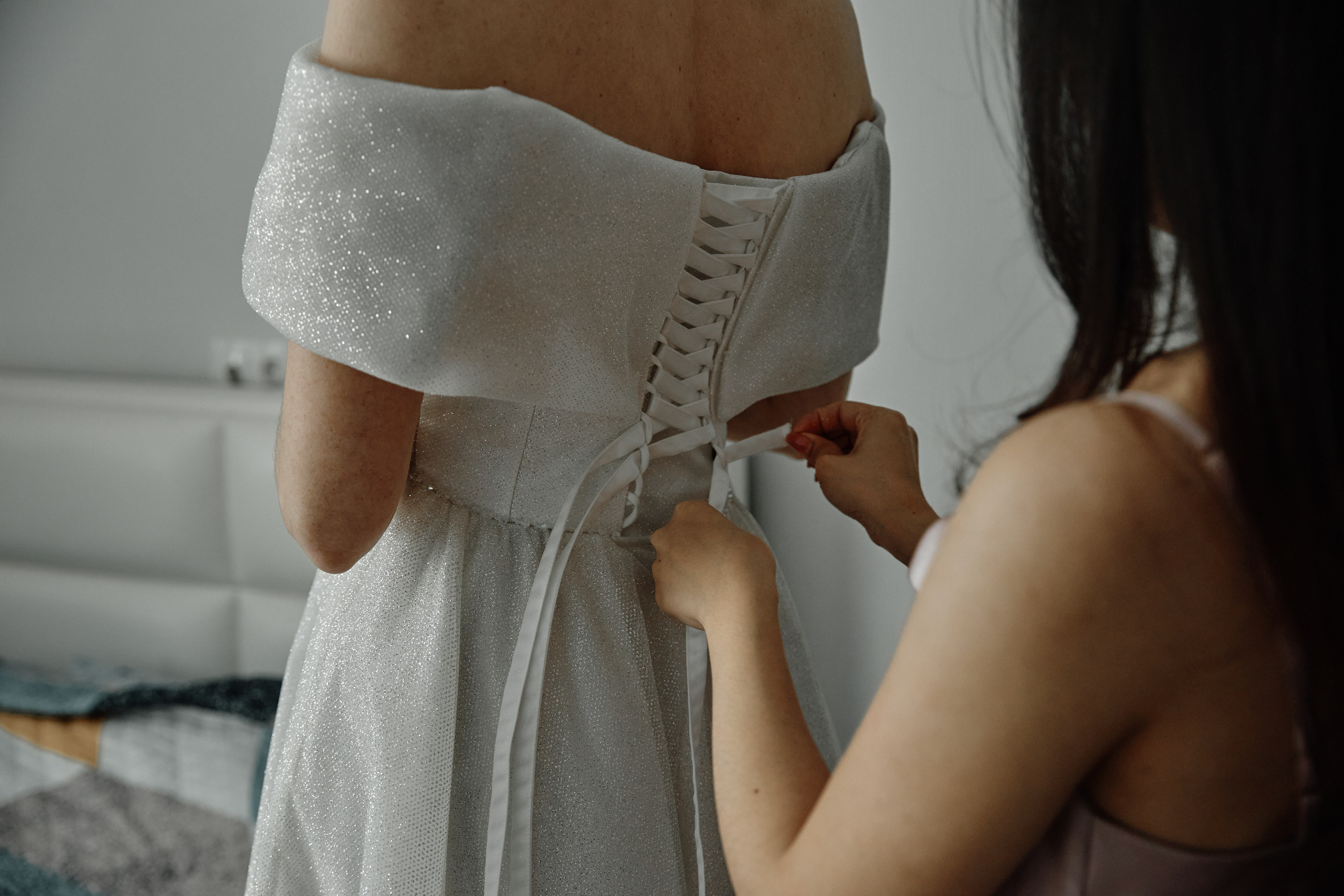 Подружка невесты помогает надевать свадебное платье