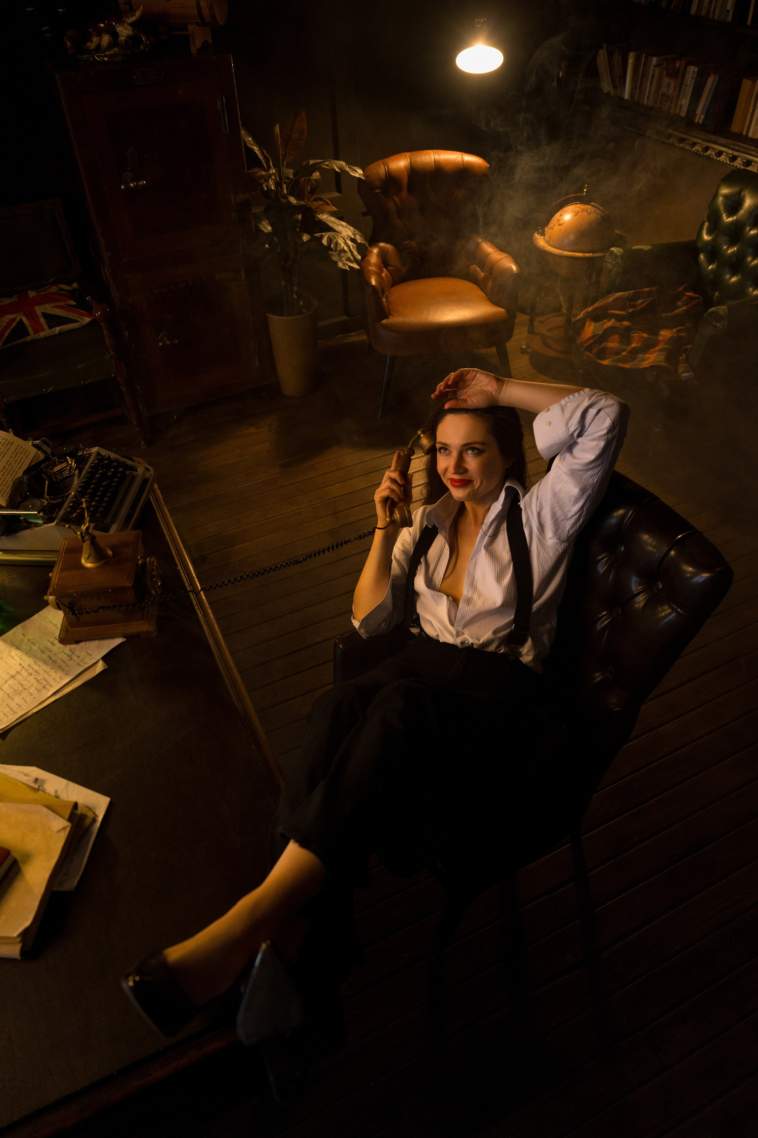 девушка сидит на стуле в задымленном помещении и говорит по телефону