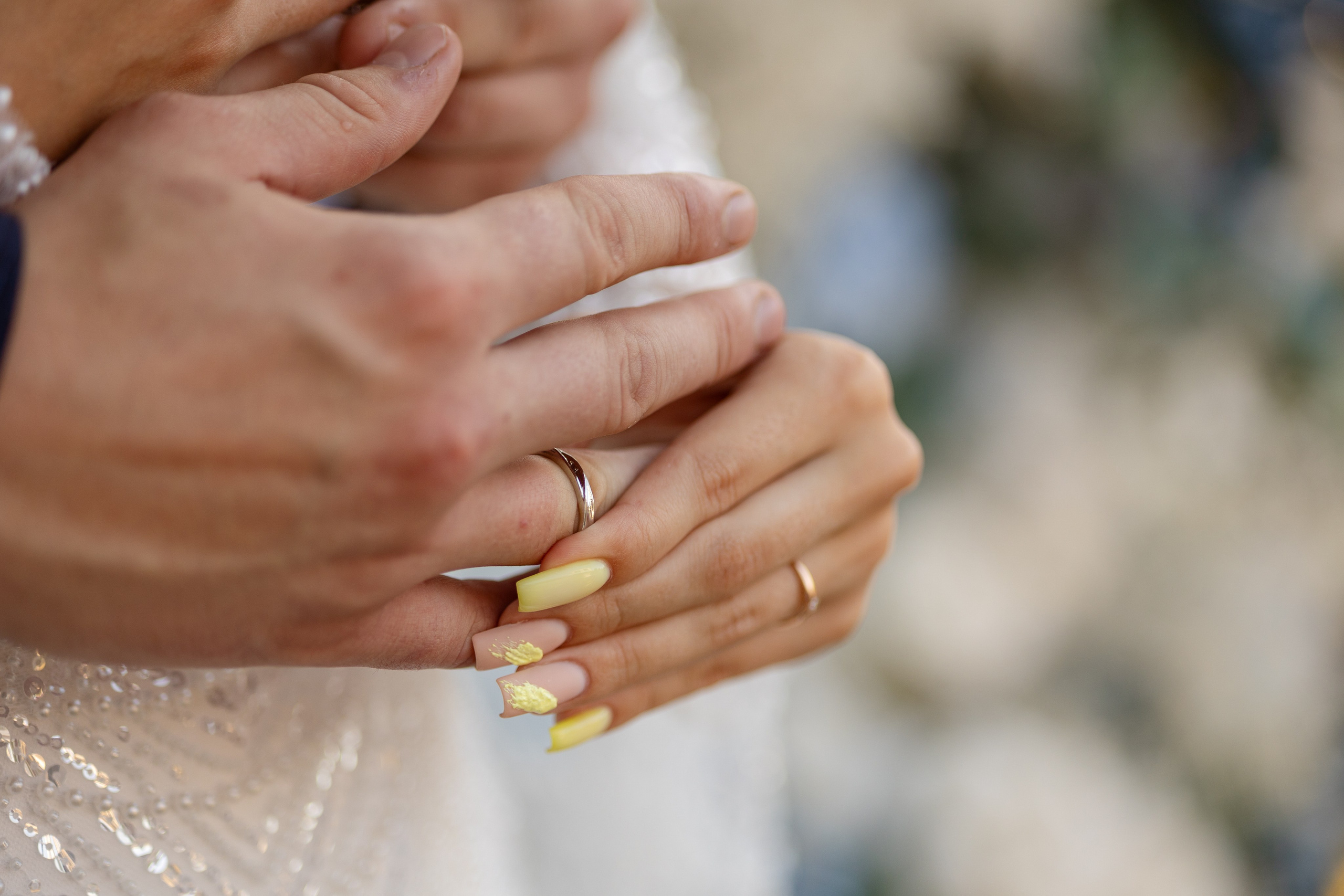 Невеста поправляет обручальное кольцо на руке жениха.