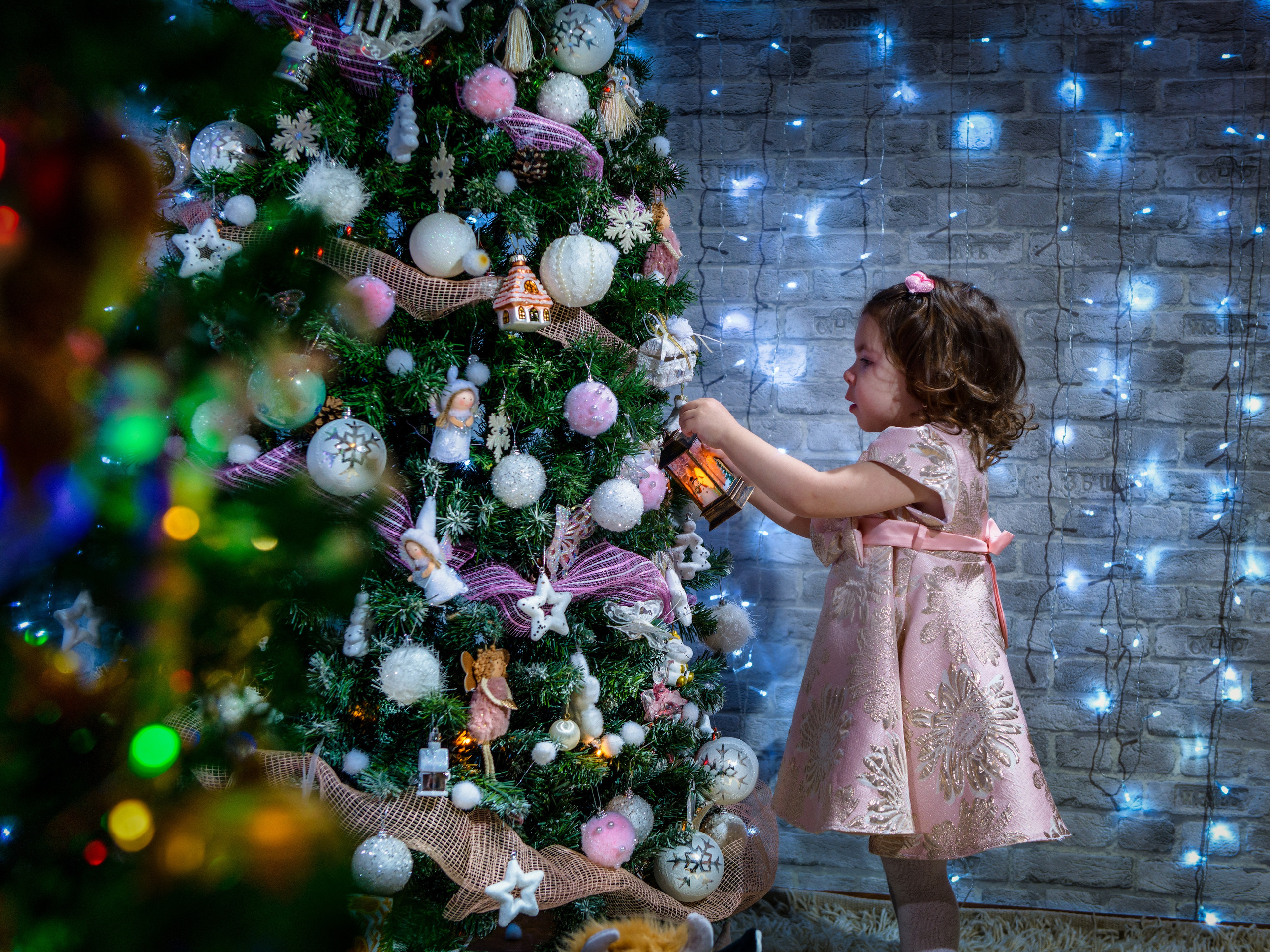 Девочка вешает шарик на новогоднюю елку
