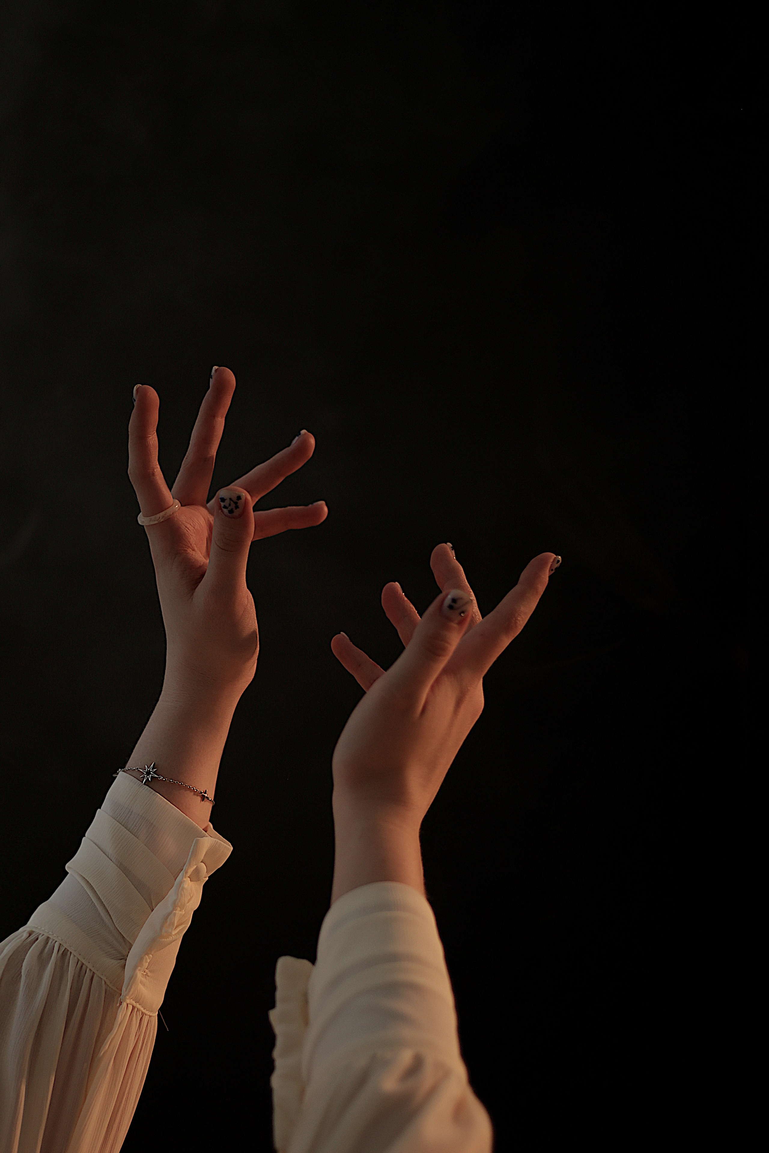 Детали тематической фотосессии: руки девушки с аккуратным маникюром и браслетами на черном фоне