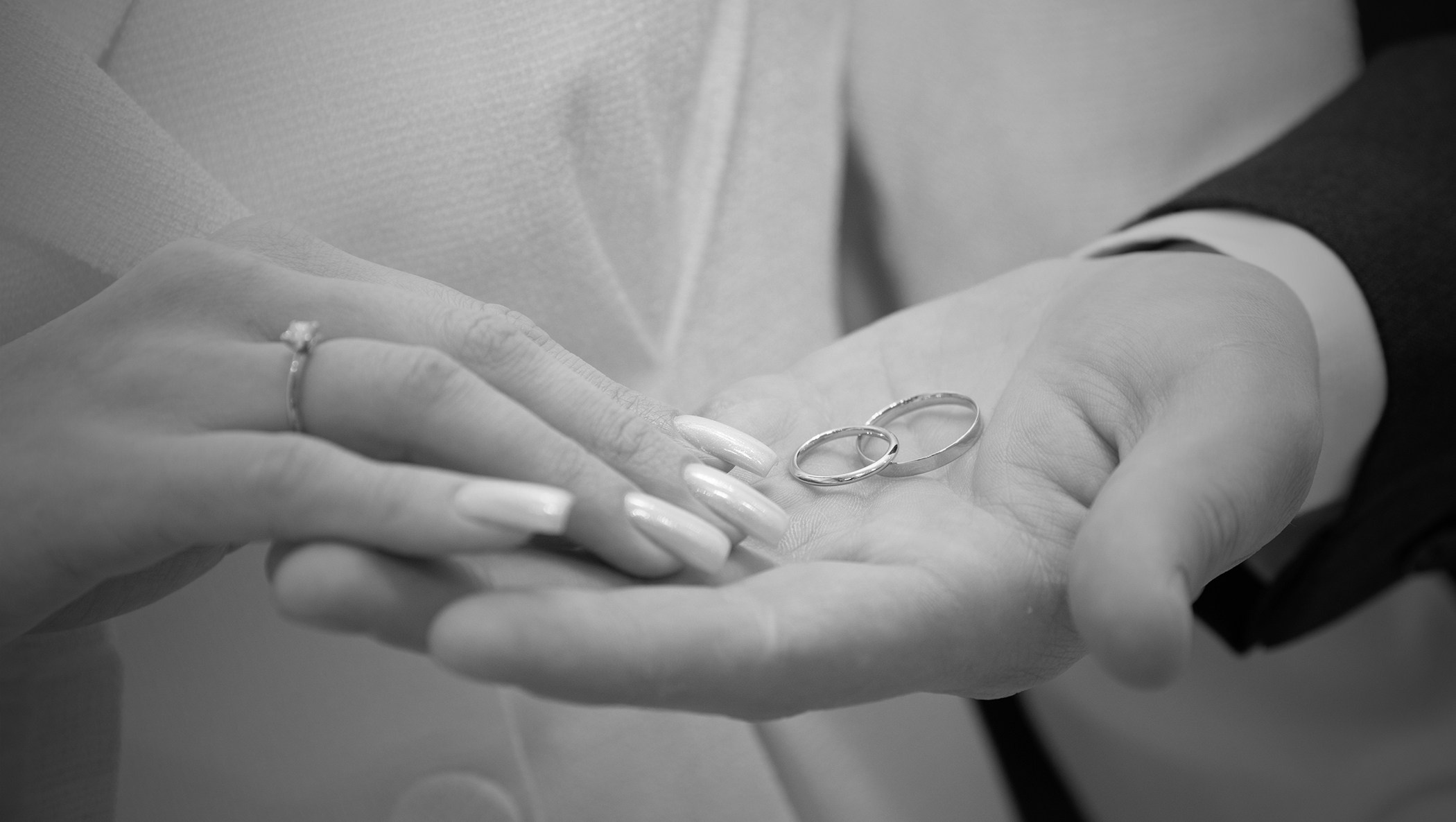 черно белое фото где невеста касается руки жениха у которого на этой руке лежат обручальные кольца 