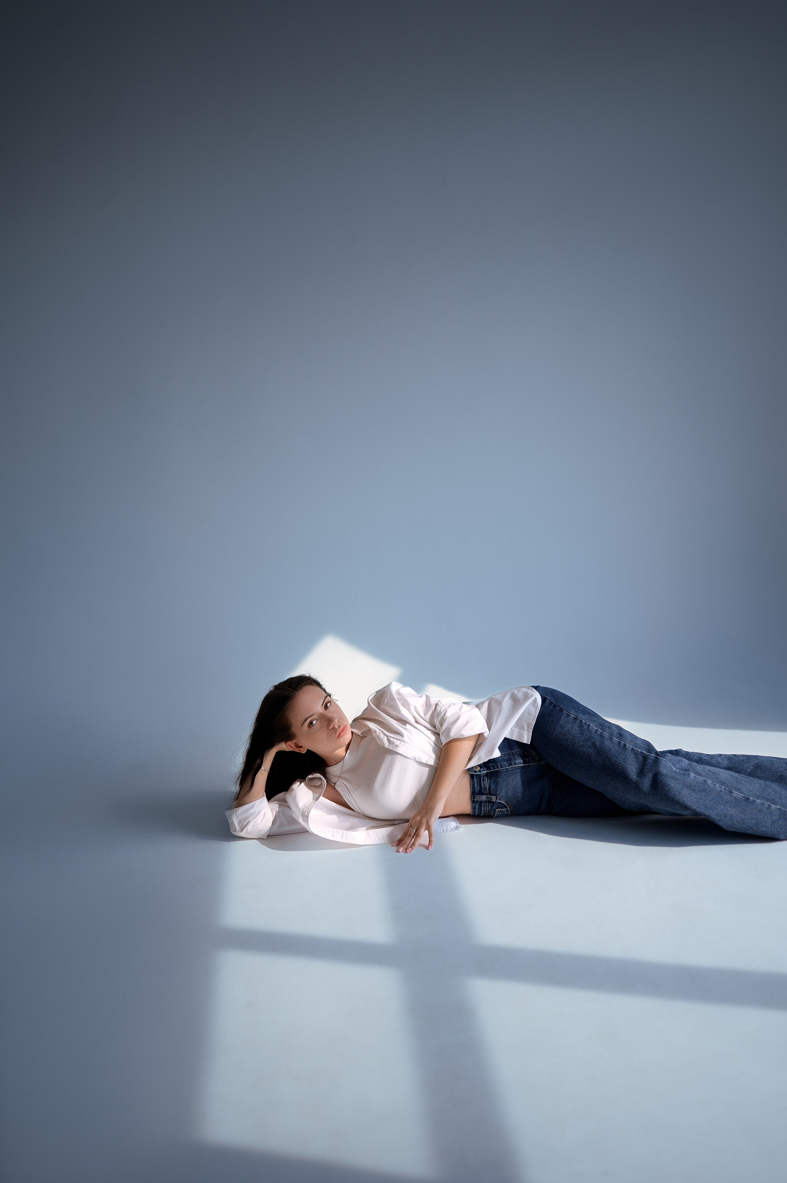 Портрет девушки в джинсах и рубашке. Съёмка на циклораме в Волгодонске. Минимализм, мягкий свет, лучи из окна — студия «Rassvet»