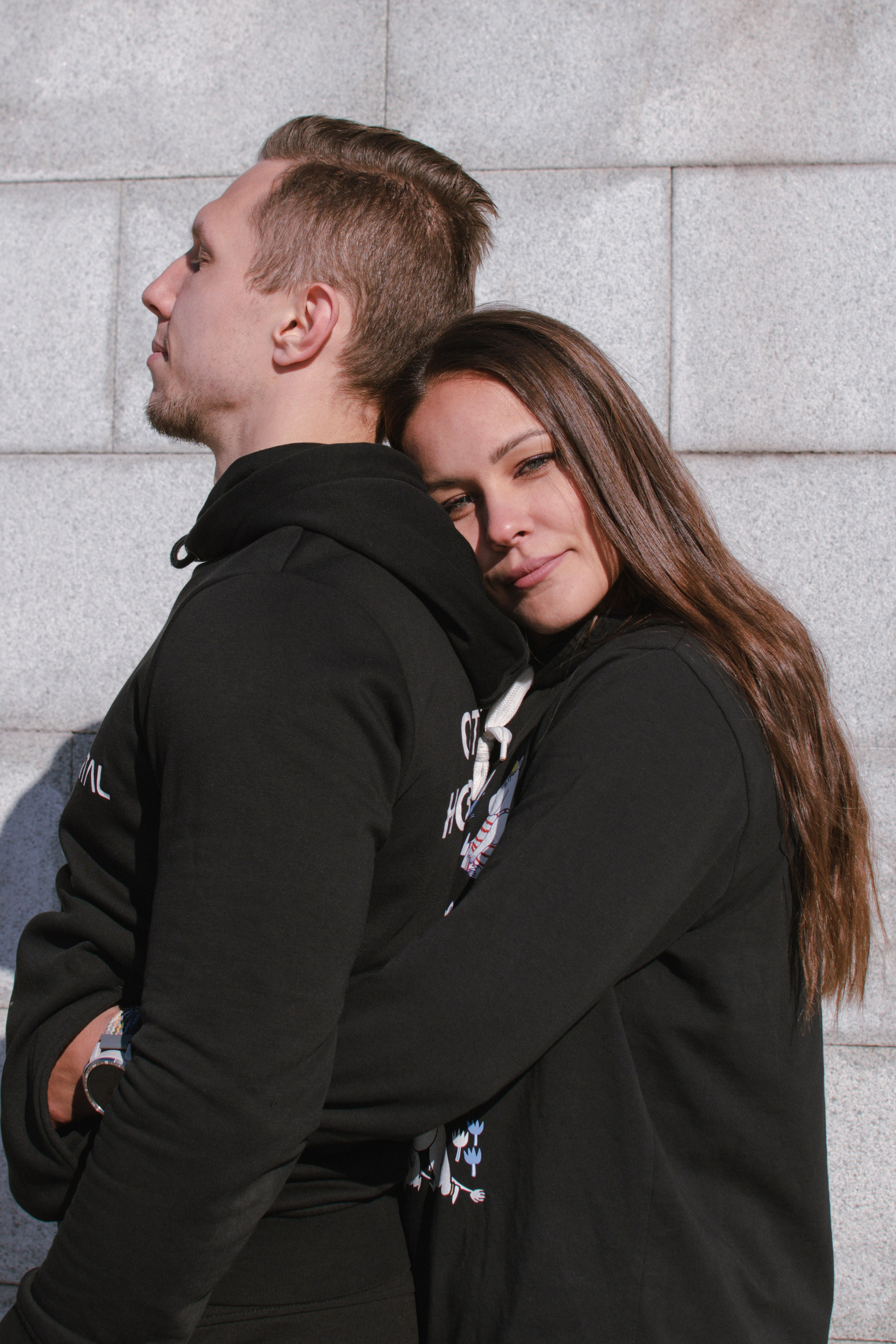 Девушка обнимает парня на фоне блочной стены