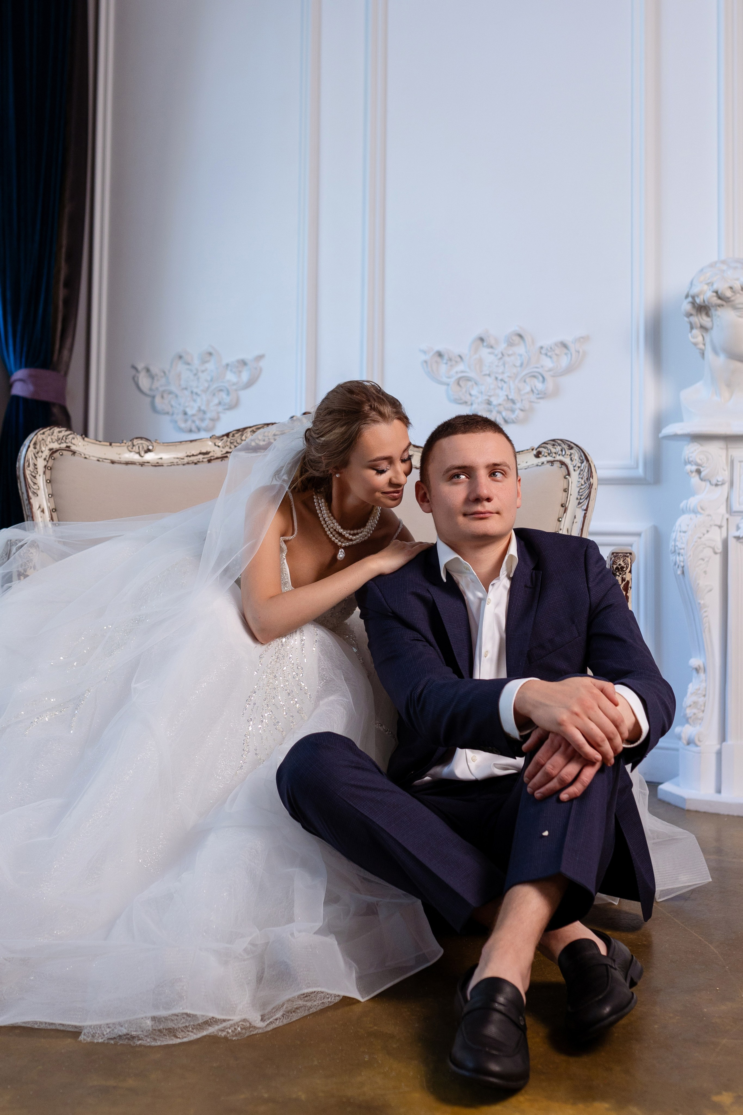 Молодые сидят на диване. Невеста наклонилась к жениху.