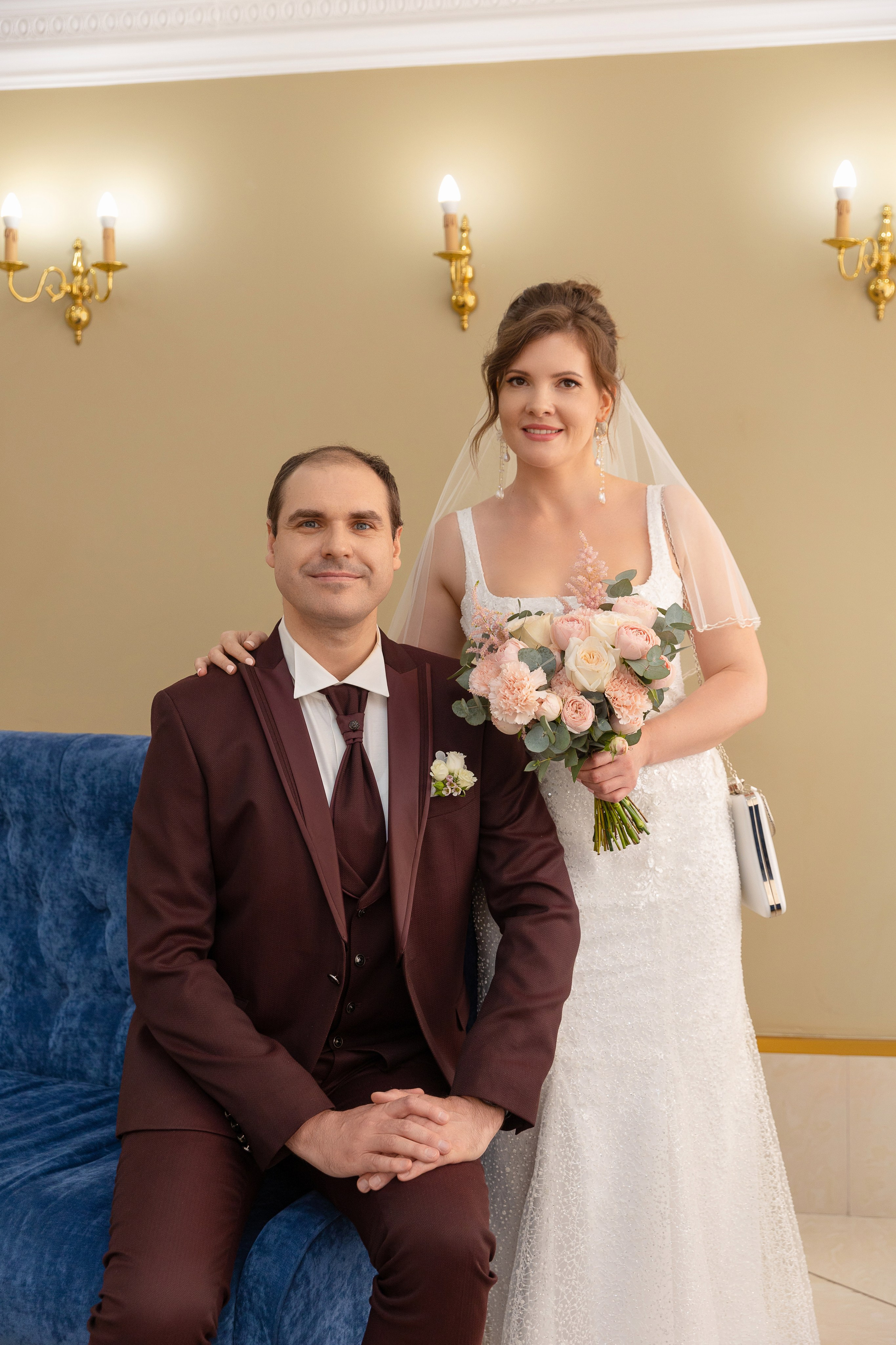 Жених в коричневом костюме стоит с любимой невестой в белом платье