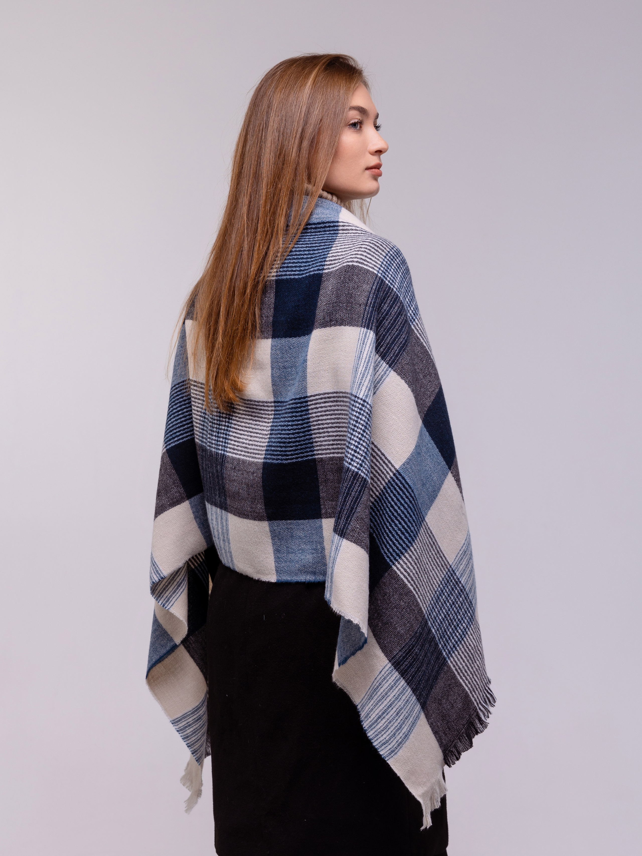 Девушка рекламирует шарф в крупную клетку, вид сзади.