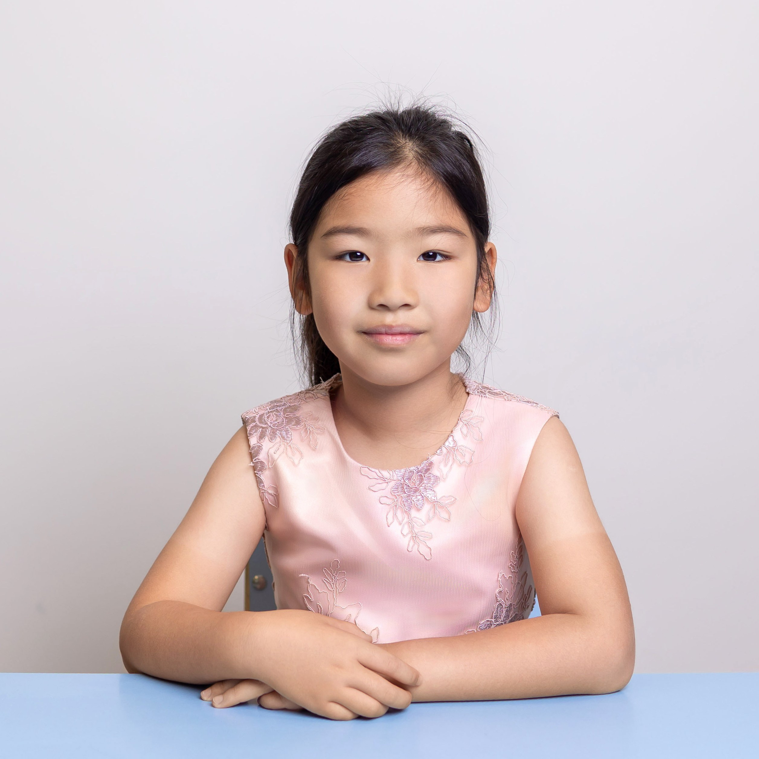 Девочка в розовом платье на светлом фоне, портрет