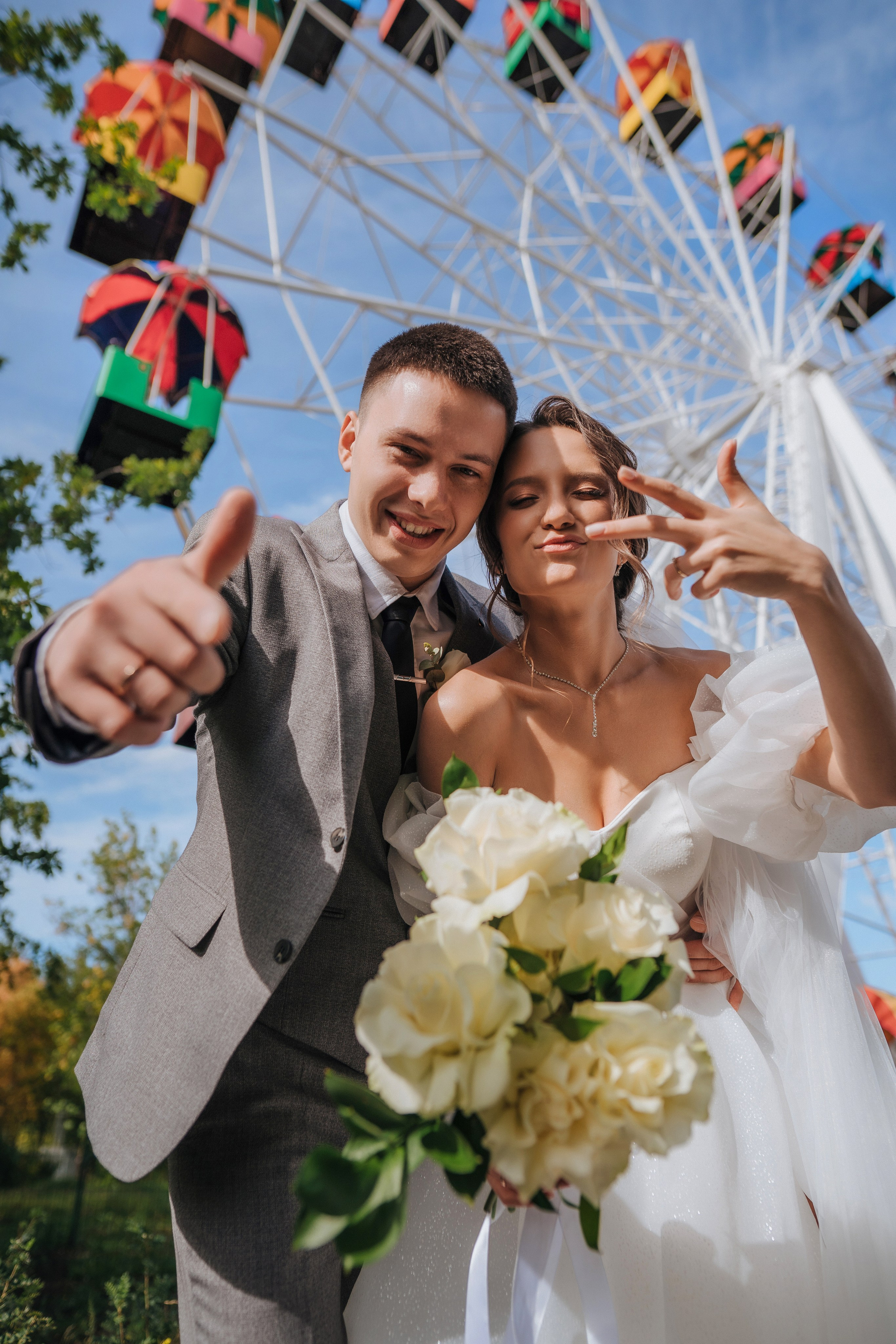 Жених и невеста в парке аттракционов, на фоне колеса обозрения