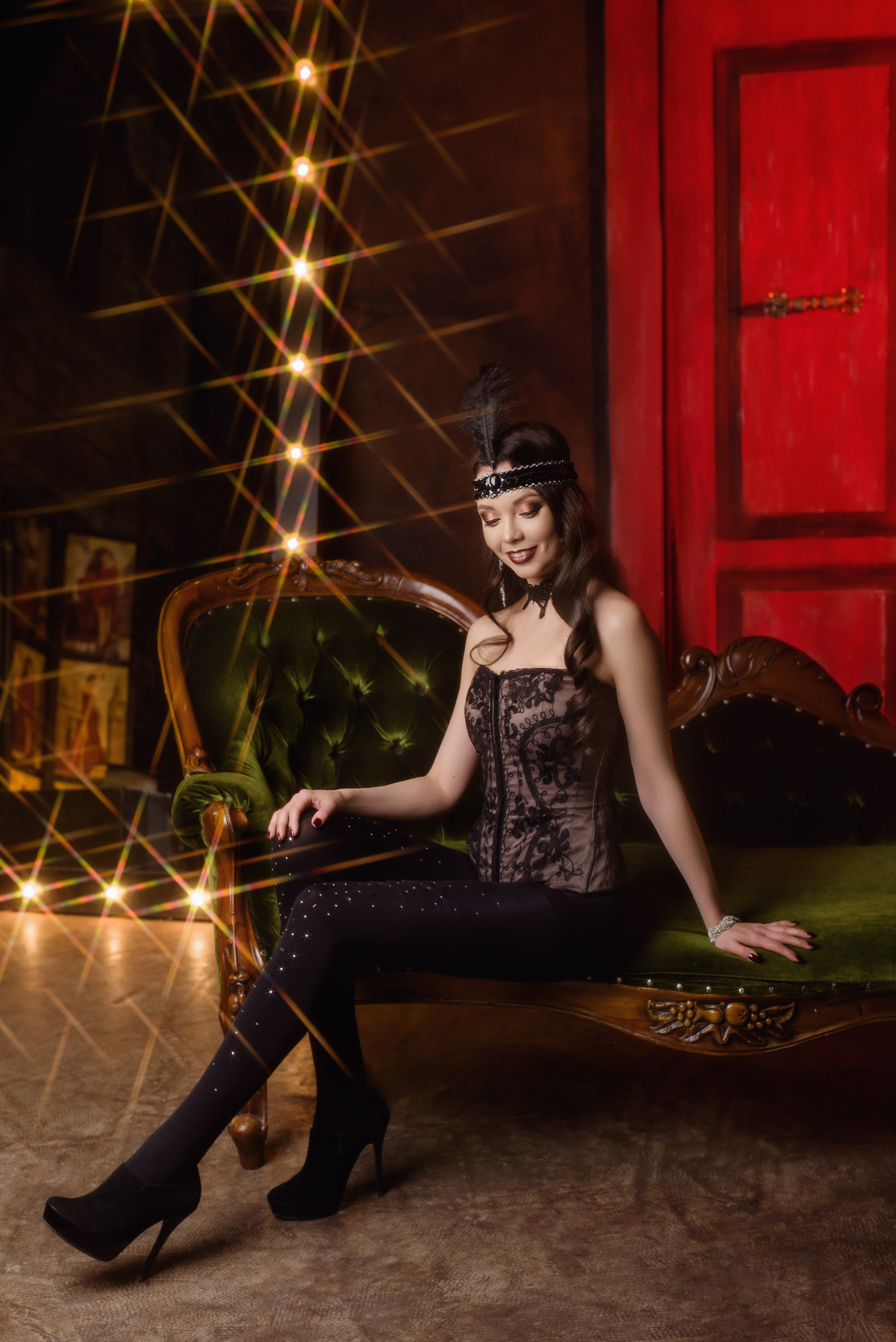 Артистка бурлеска позирует после спектакля в гримерной на фоне огней и красной двери