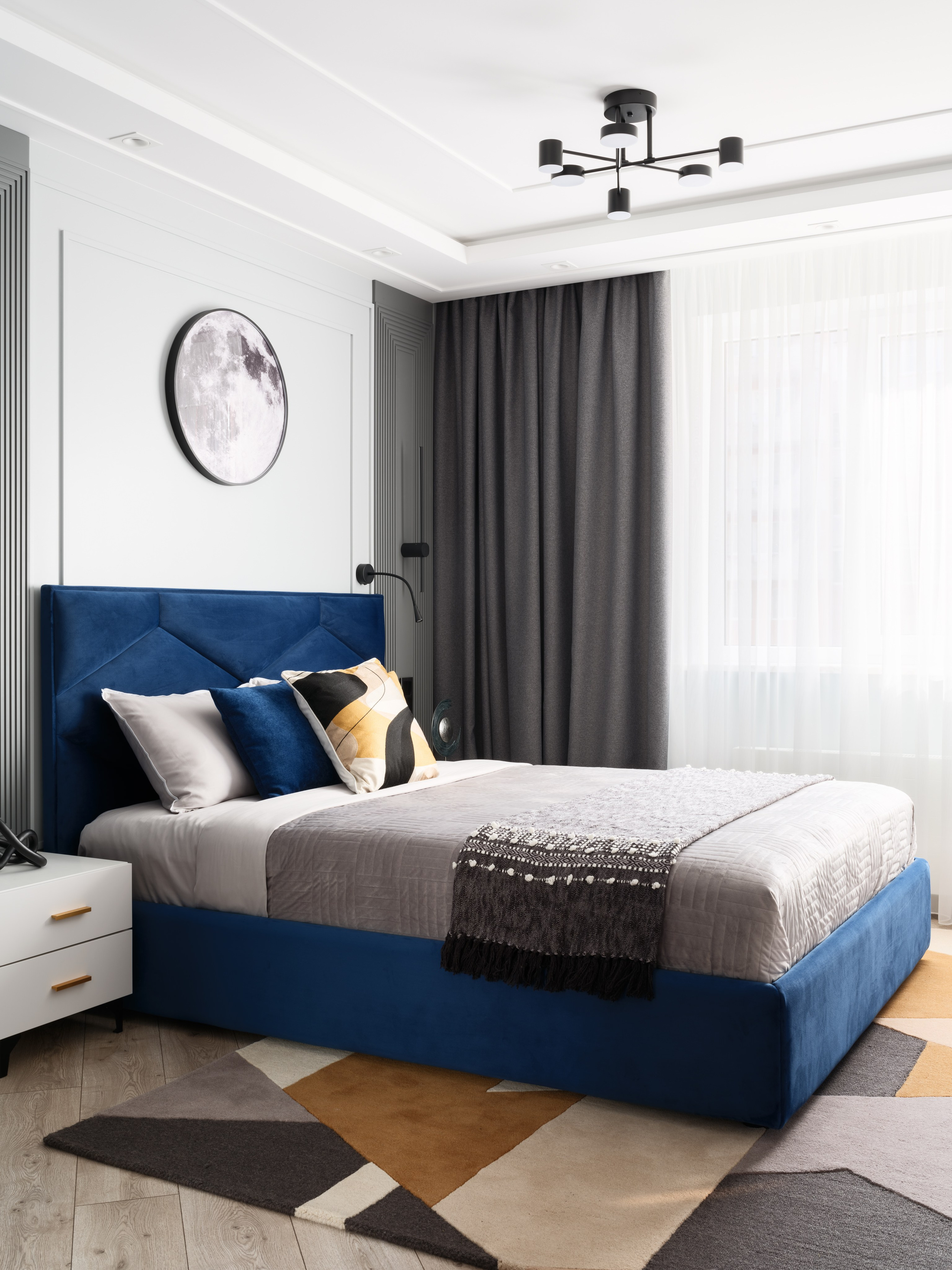 Интерьер спальни в современном стиле: геометрический ковёр, серое покрывало, контрастные подушки и акценты в синем и горчичном цветах. Автор дизайна Евгения Ермошина, съёмка Сергея Денисенко — стильное фото современного интерьера.