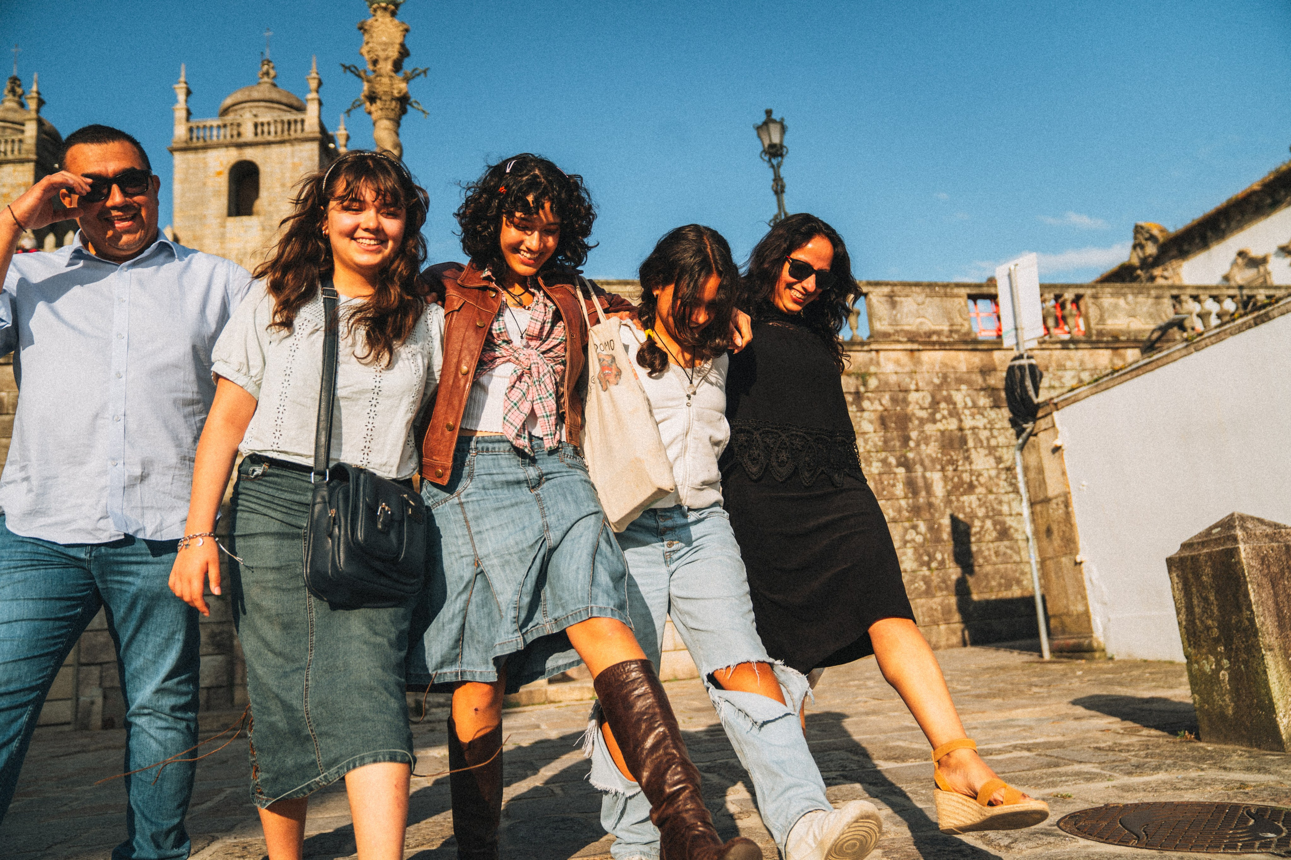 Группа людей гуляет по живописной узкой улочке в Португалии, окружённой старыми домами и зеленью.